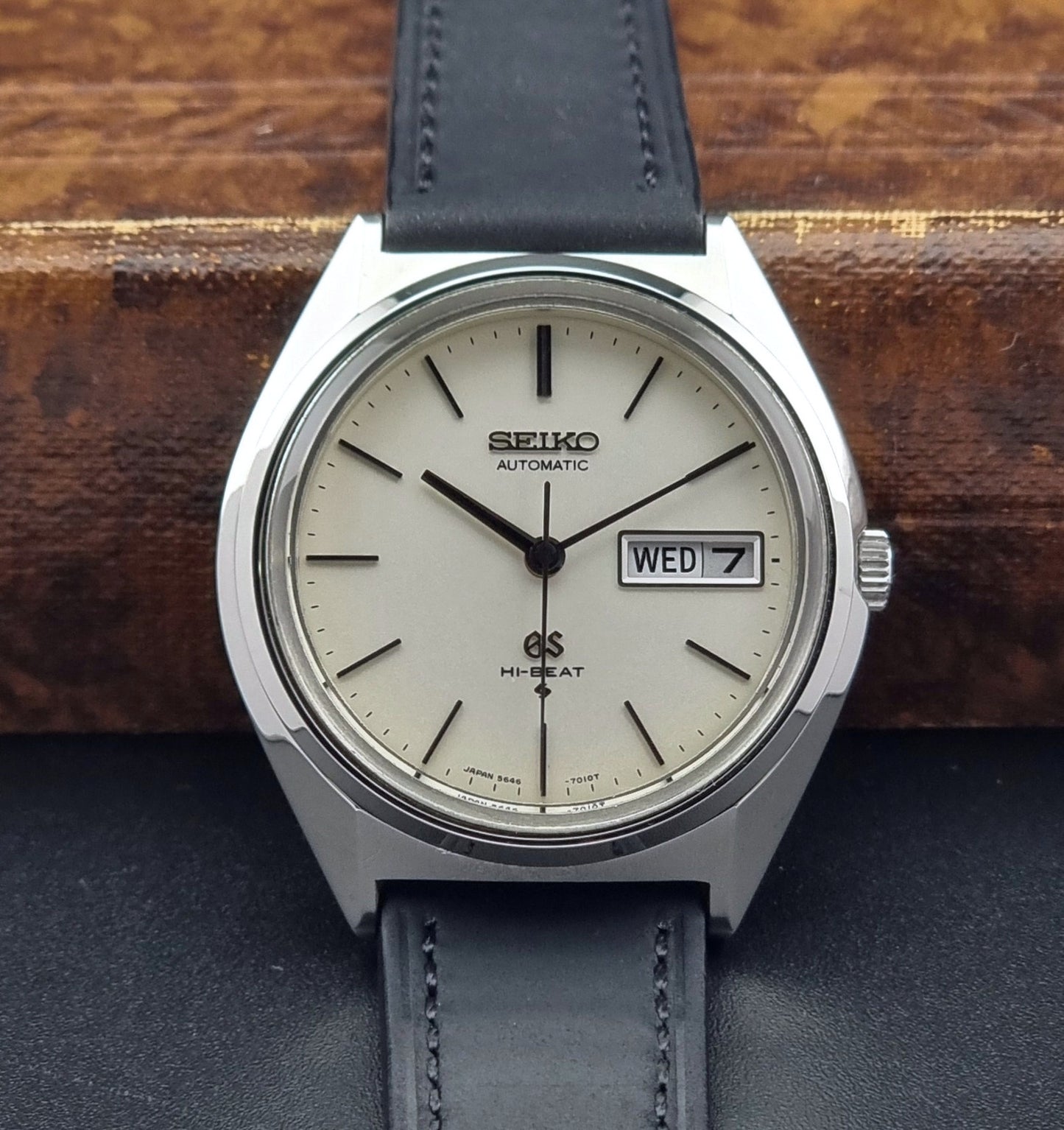 Vintage Grand Seiko 5646-7011 Wristwatch with black leather strap on a wooden surface close up dial