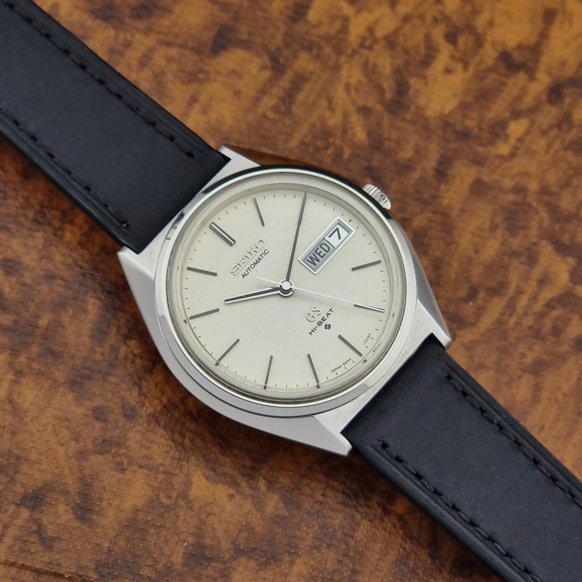 Vintage Grand Seiko 5646-7011 Wristwatch with black leather strap on a wooden surface