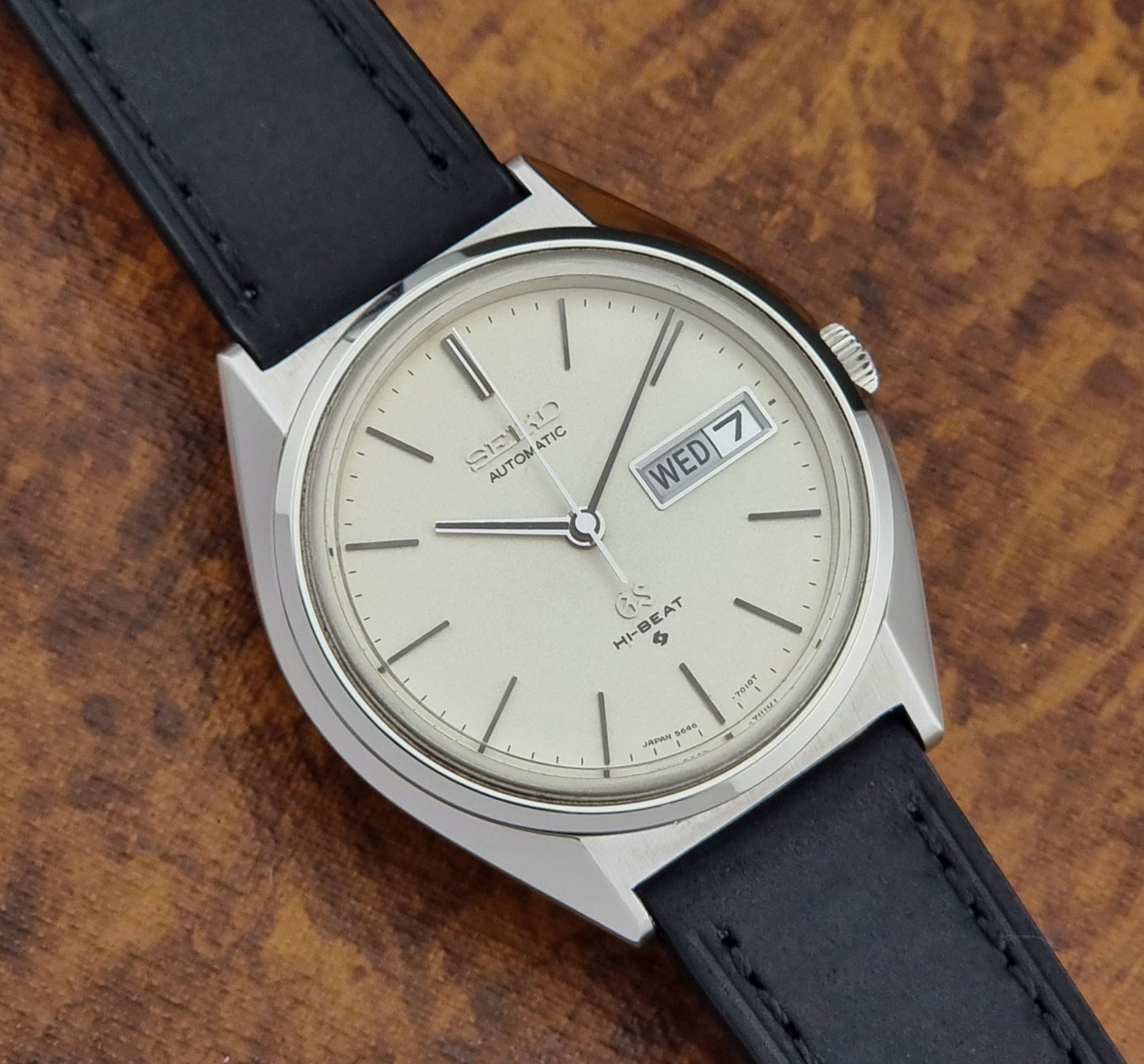 Vintage Grand Seiko 5646-7011 Wristwatch with black leather strap on a wooden surface close up dial