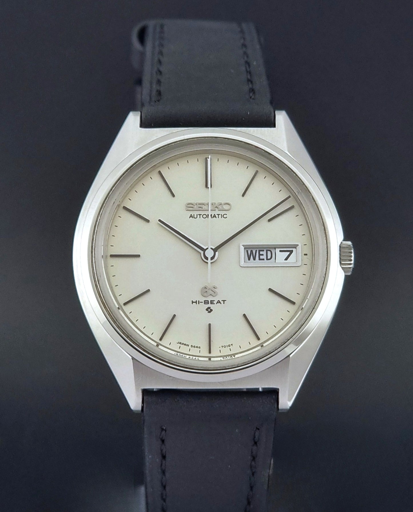 Vintage Grand Seiko 5646-7011 Wristwatch with black leather strap on a wooden surface close up