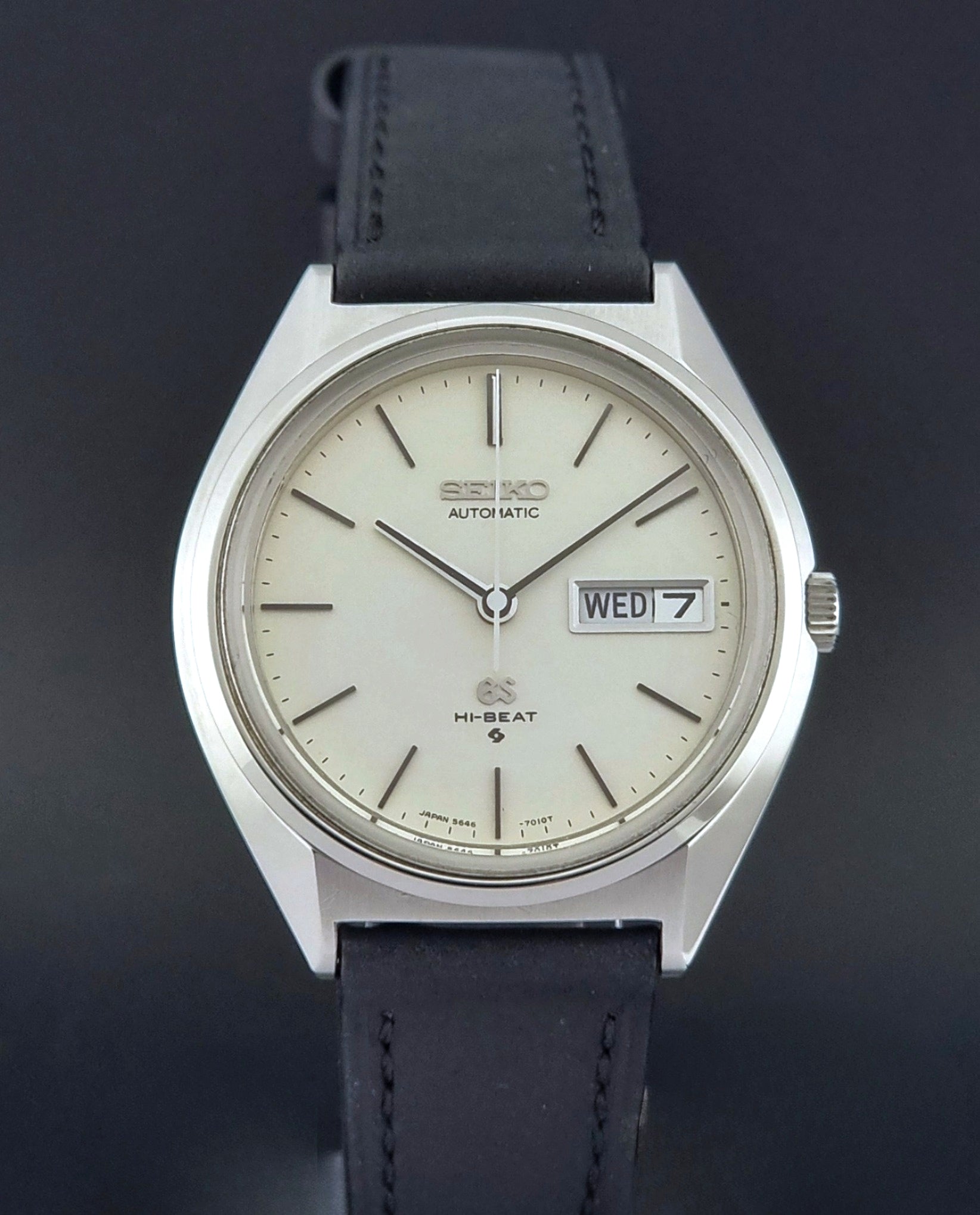 Vintage Grand Seiko 5646-7011 Wristwatch with black leather strap on a wooden surface close up
