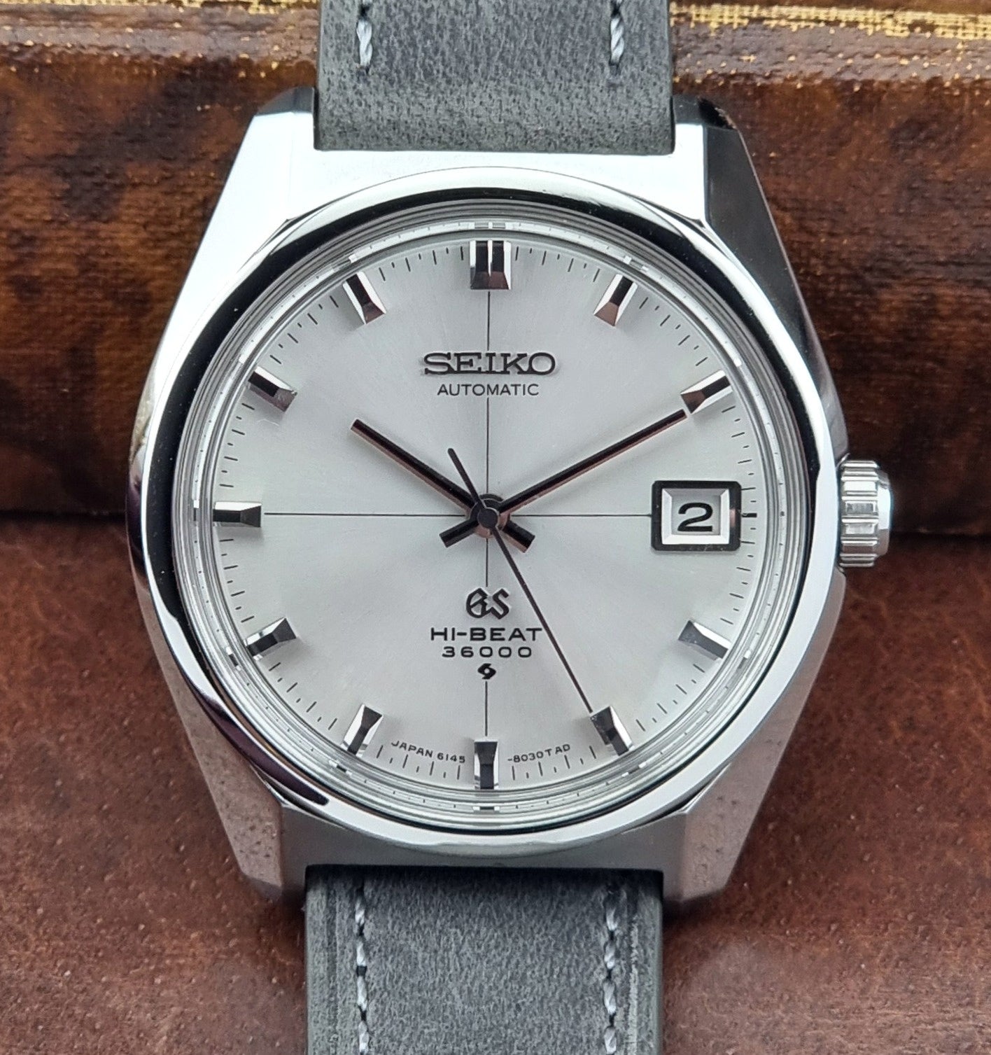 Vintage Grand Seiko watch with gray leather strap on a wooden surface