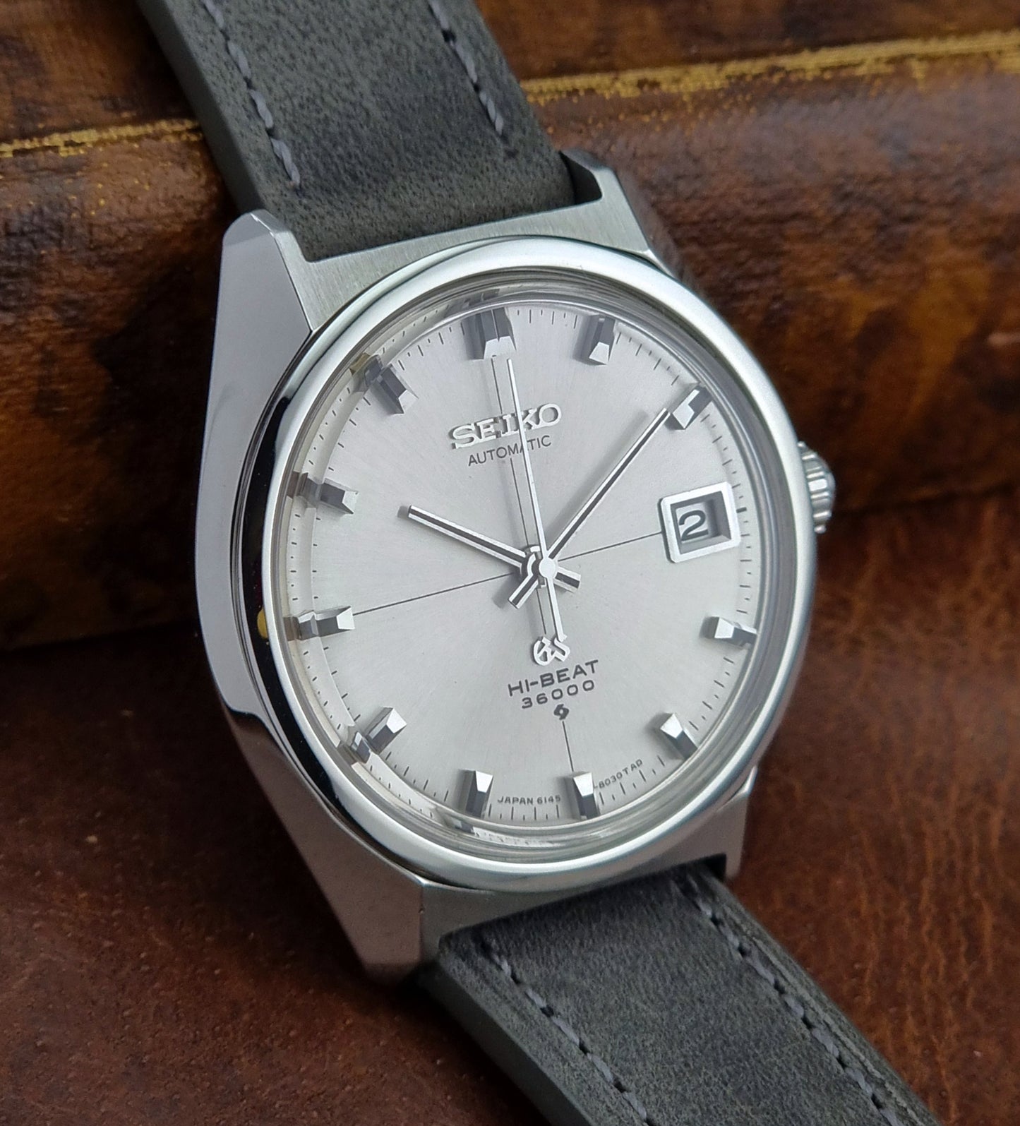Vintage Grand Seiko watch with gray strap on a wooden surface