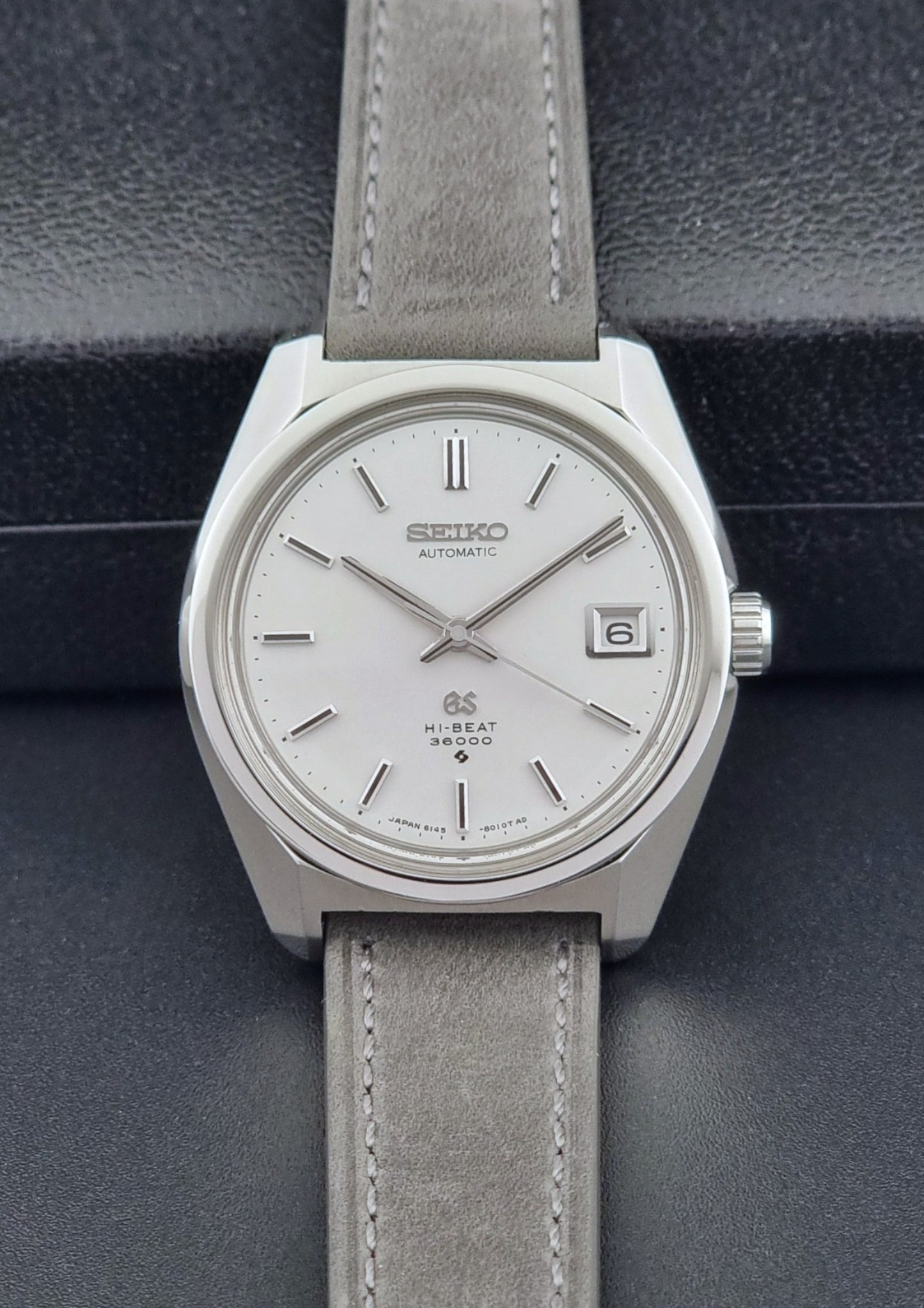Grand Seiko 6145-8000 watch with gray leather strap on a dark background