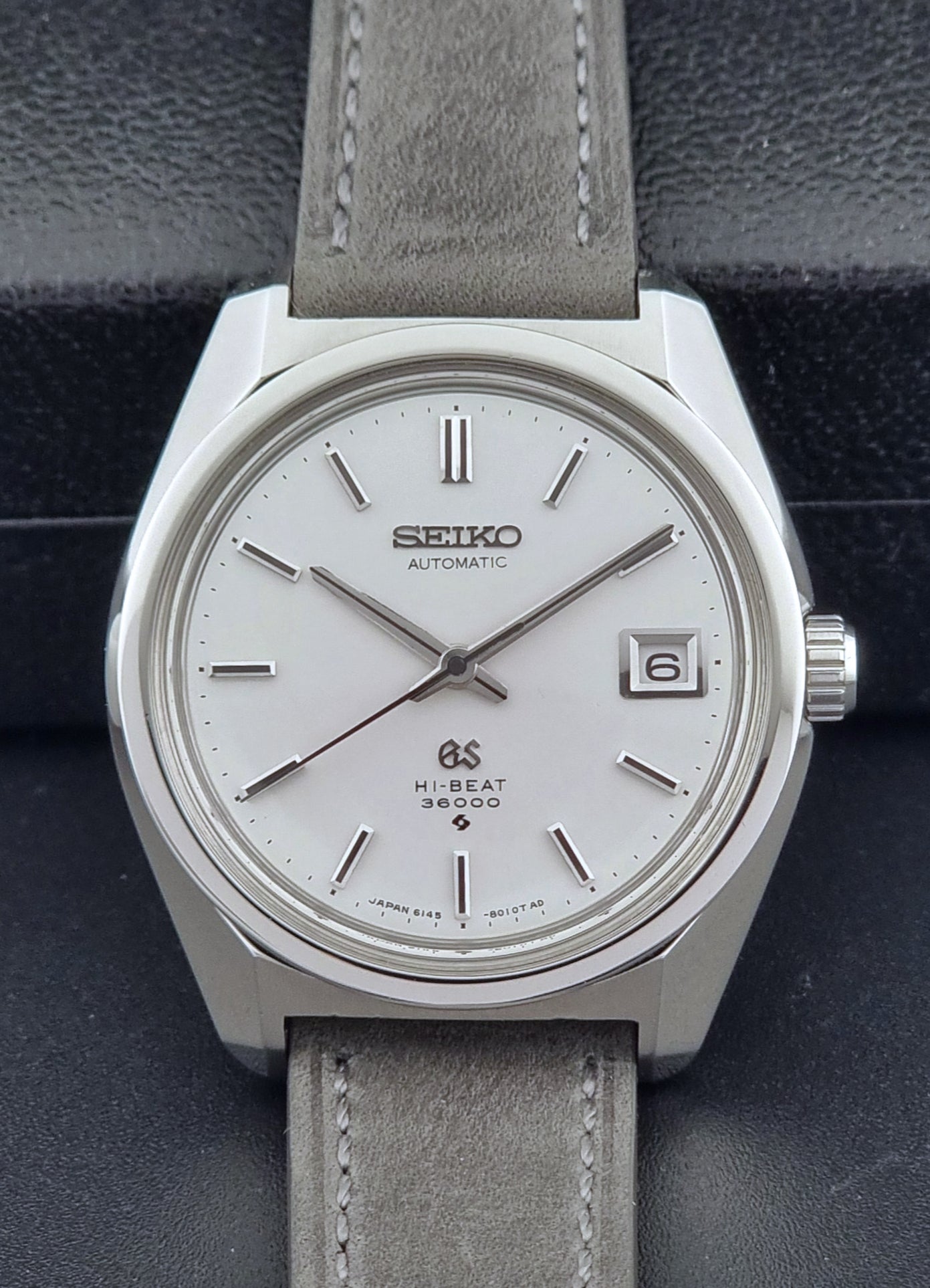 Grand Seiko 6145-8000 watch with gray leather strap on a dark background
