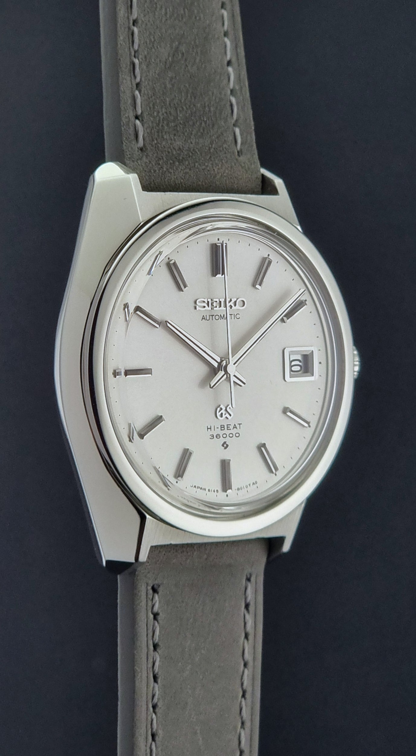 Grand Seiko 6145-8000 watch with gray leather strap on a dark background