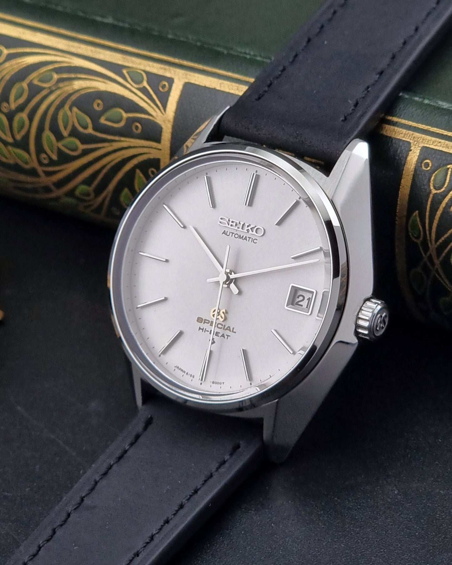 Vintage Grand Seiko Wristwatch with black strap and silver case on a dark surface