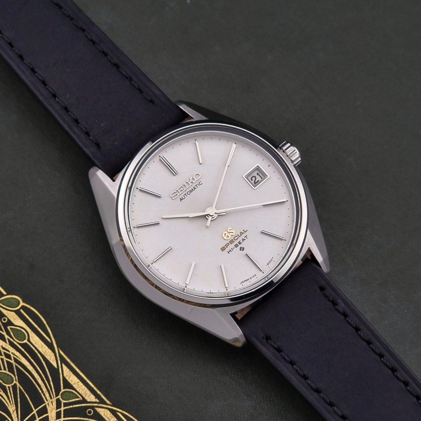 Vintage Grand Seiko Wristwatch with black strap and silver case on a dark background
