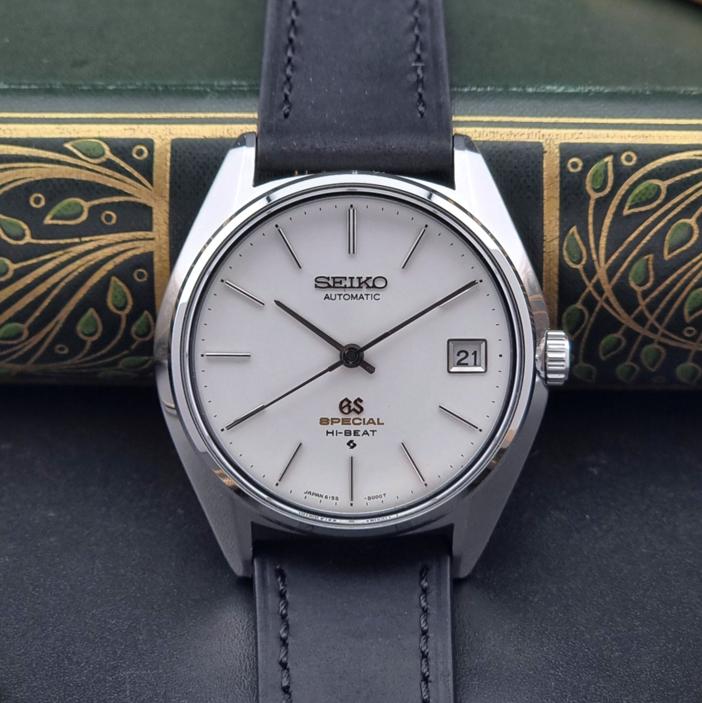 Vintage Grand Seiko watch watch with black leather strap on a decorative background