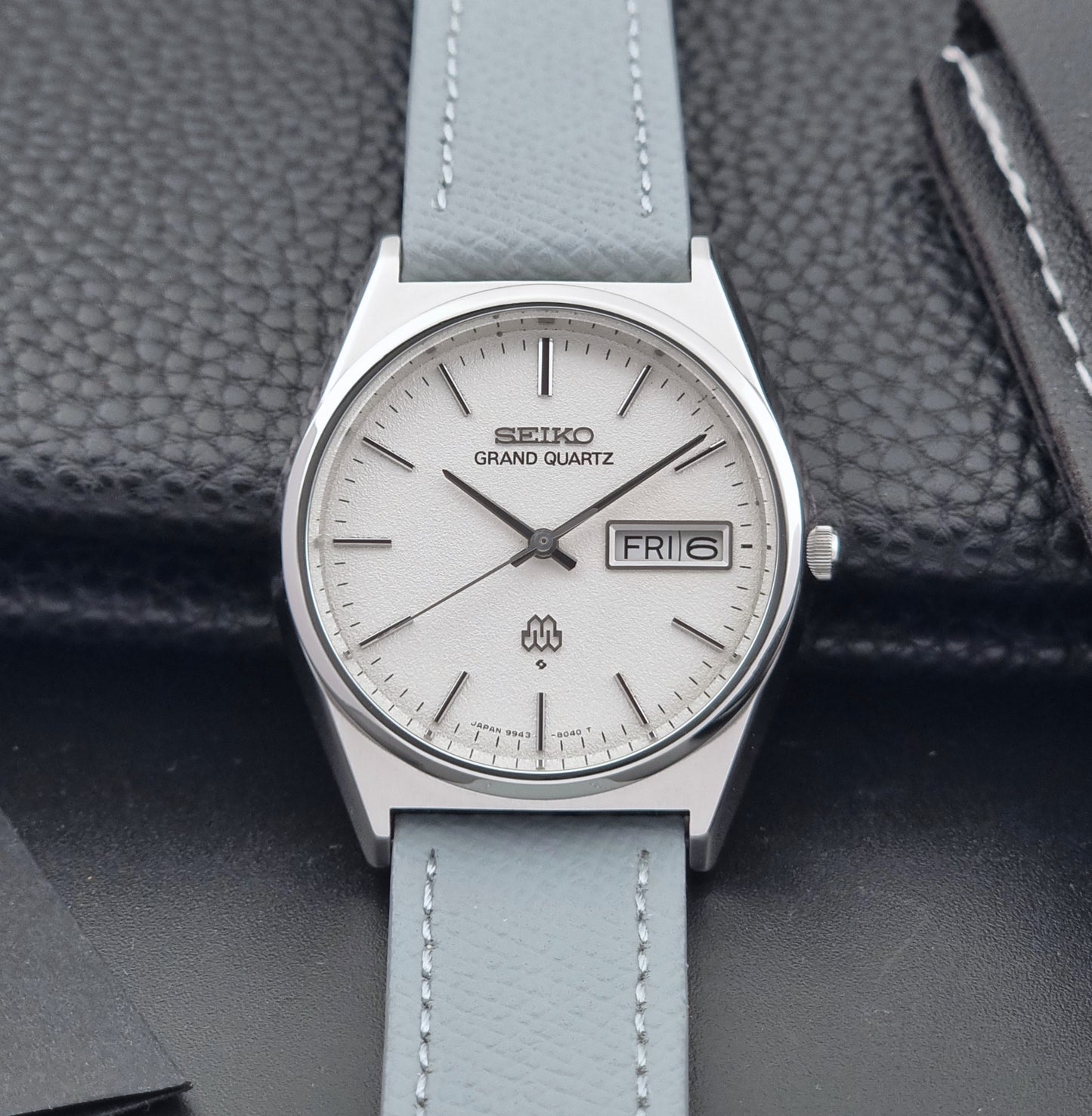Vintage Seiko Grand Quartz watch 9943-8030 with a leather strap on a dark gray background front view