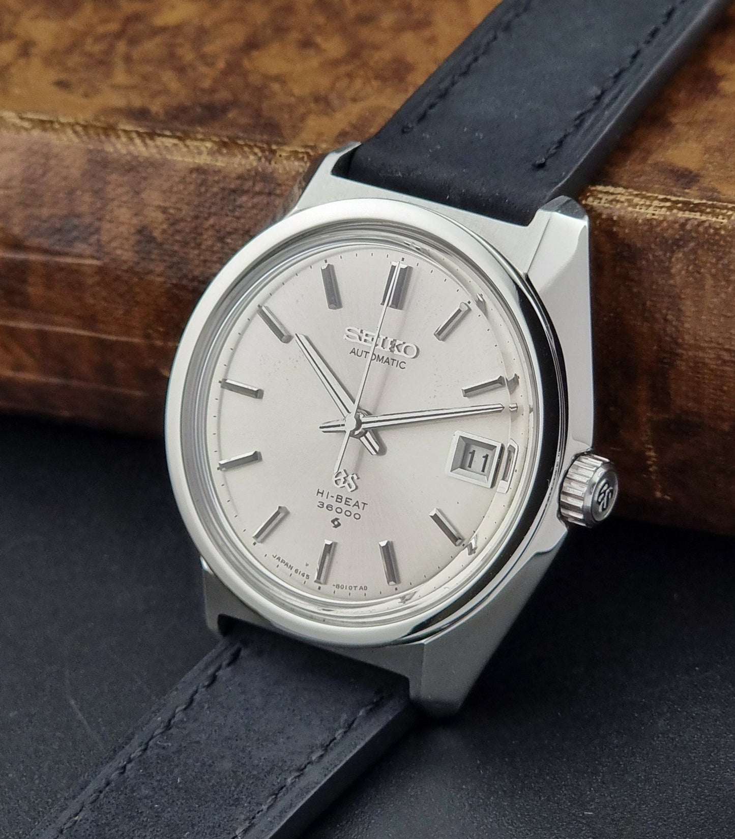 Seiko watch with silver dial and black leather strap on a wooden surface