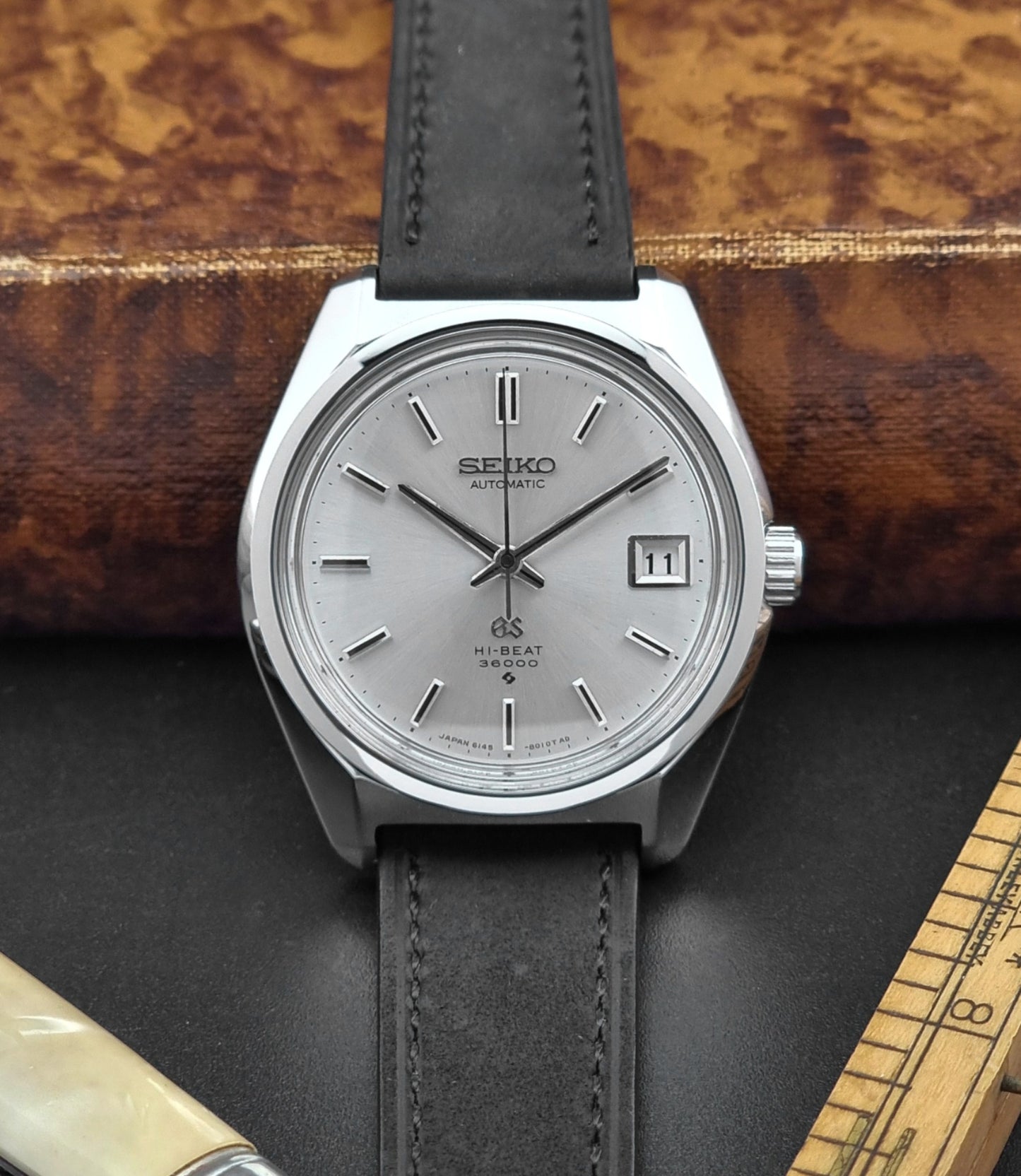 Seiko watch with a dark leather strap on a wooden surface