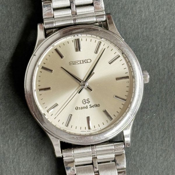 Silver Grand Seiko watch with beige dial on a gray background