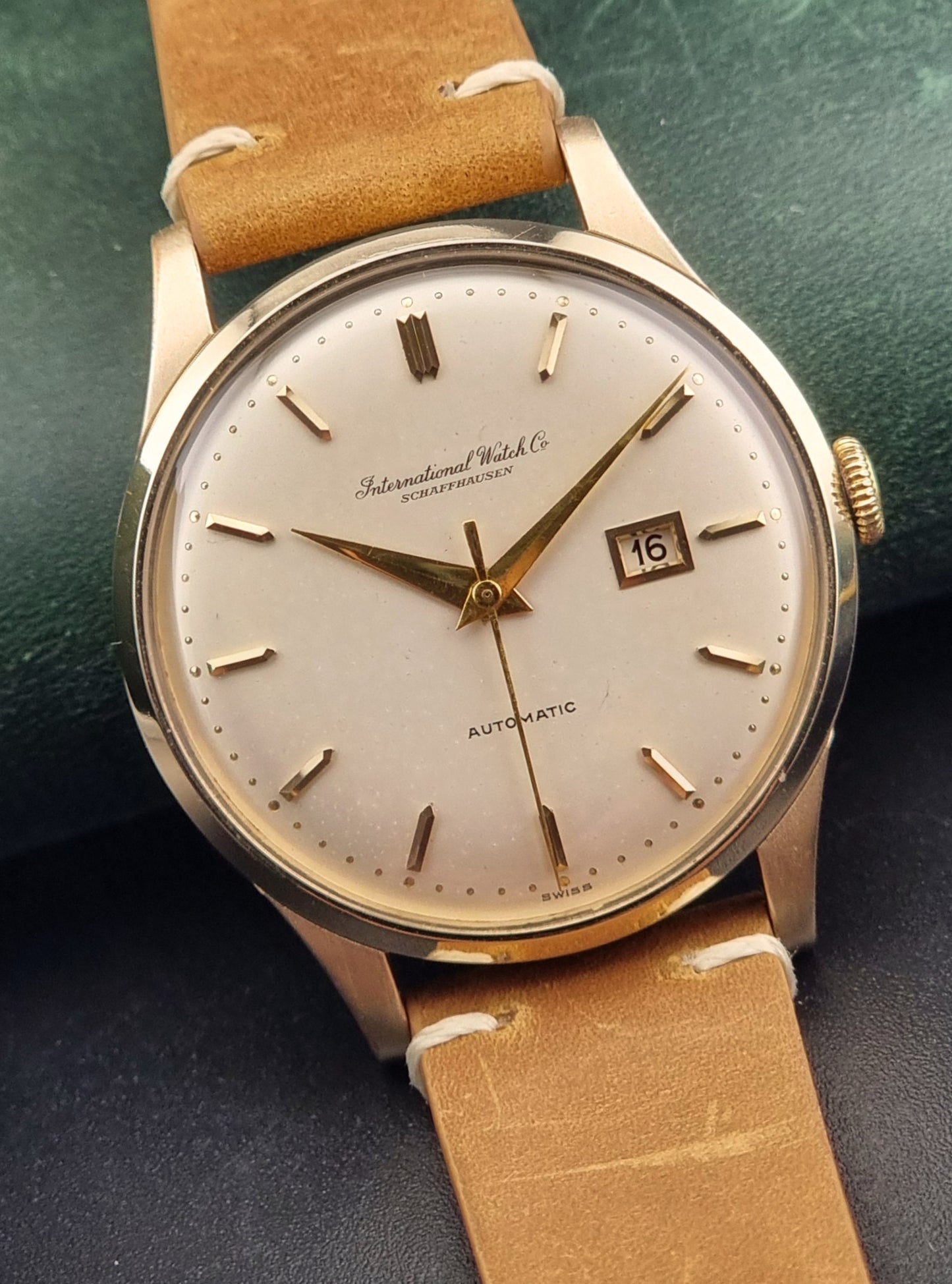 Vintage IWC wristwatch with a brown leather strap on a dark background
