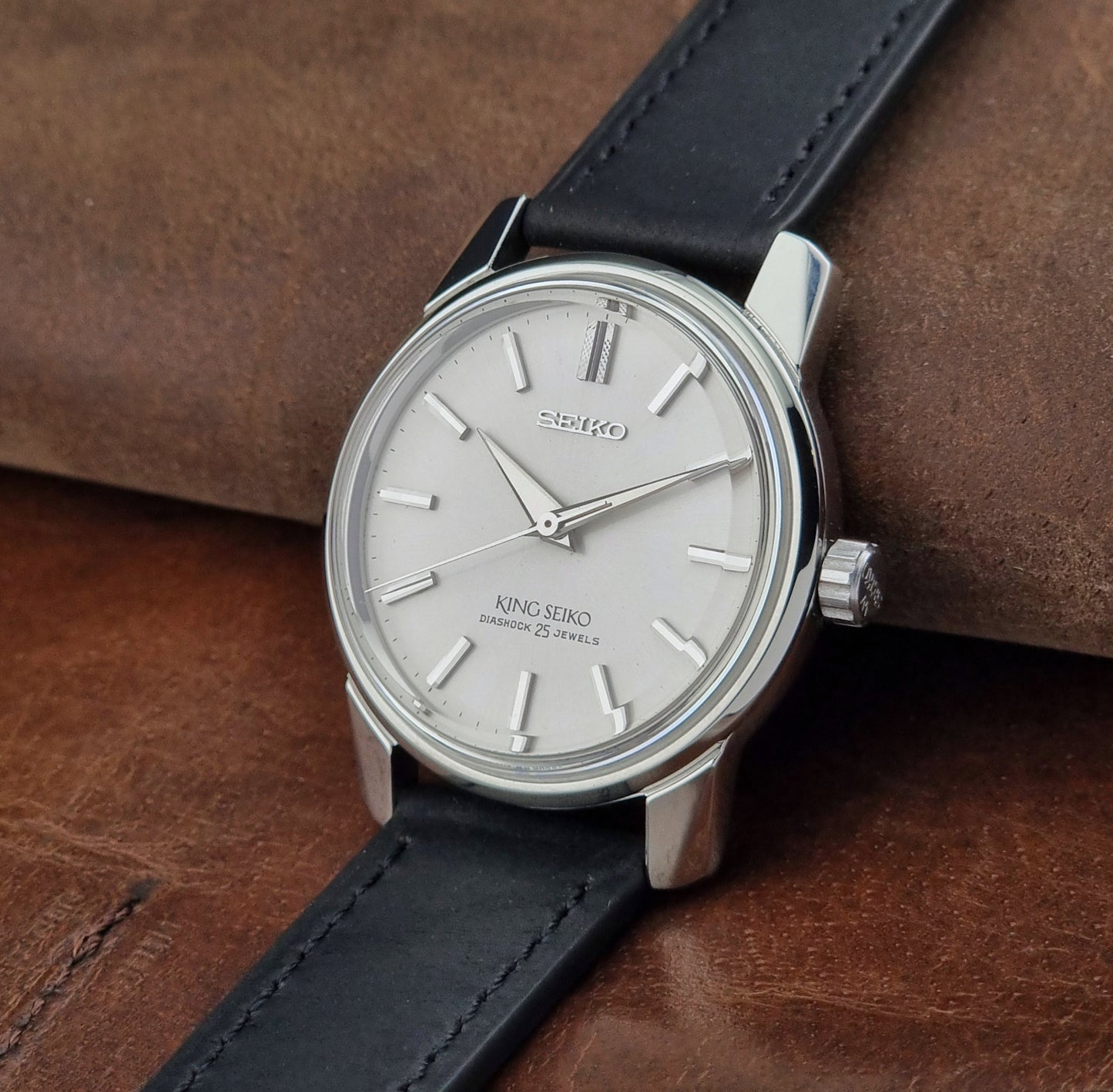Vintage King Seiko 44-999 Watch with black leather strap on a brown textured background