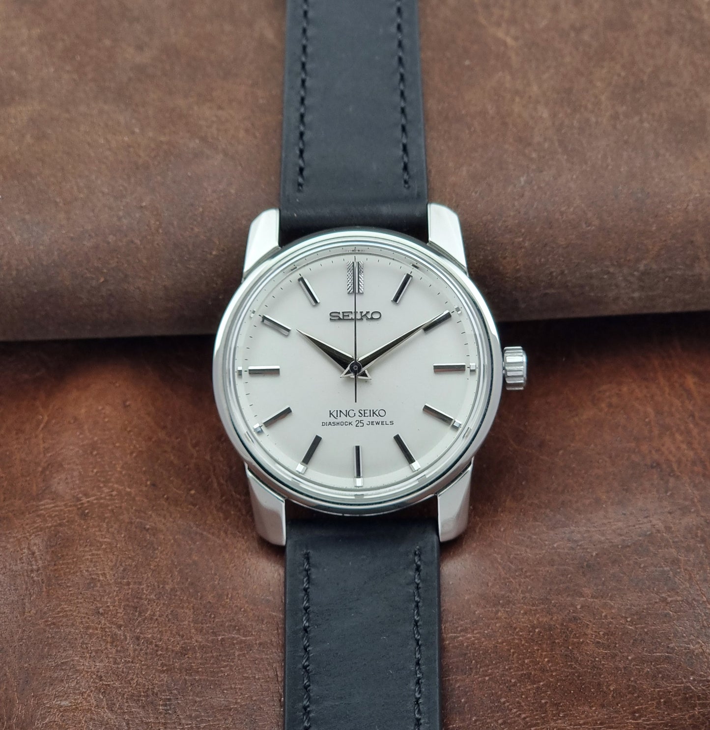 Vintage King Seiko 44-999 Watch with black leather strap on a brown leather background