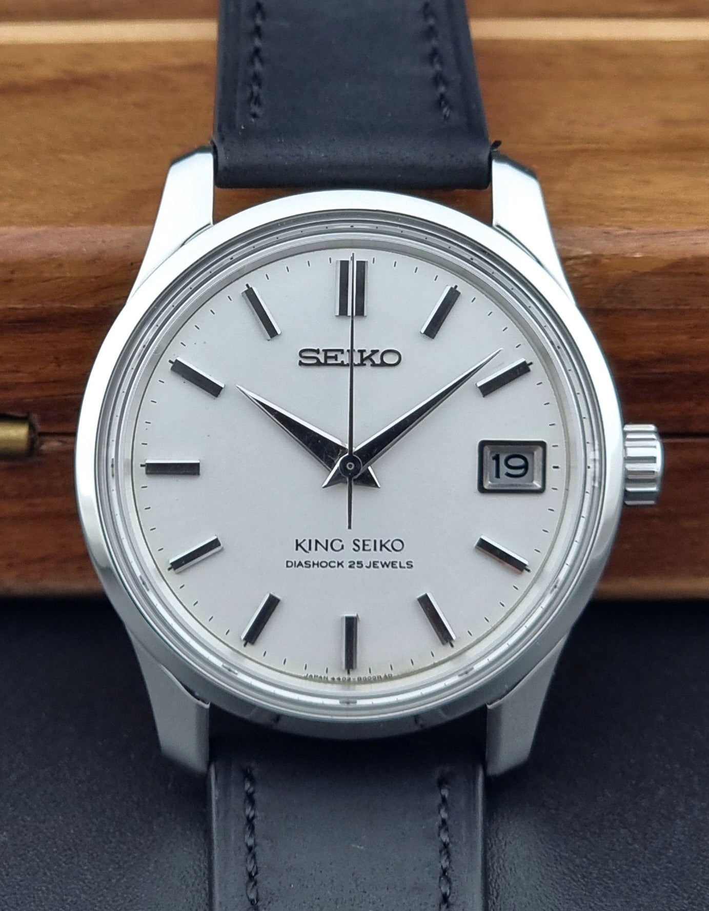 Vintage King Seiko 4402-8000 watch with black leather strap on a wooden surface