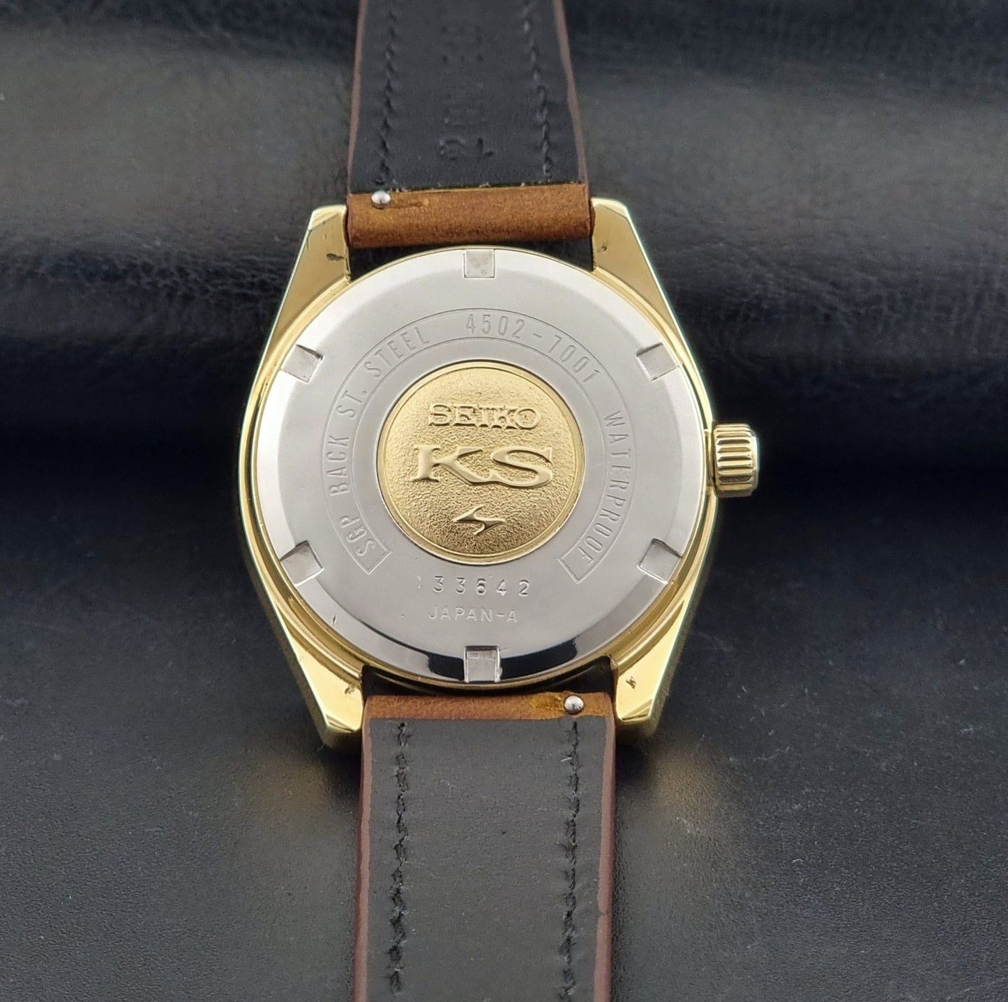 Vintage King Seiko Wristwatch 4502-7001 brown leather strap on a dark gray background case back view