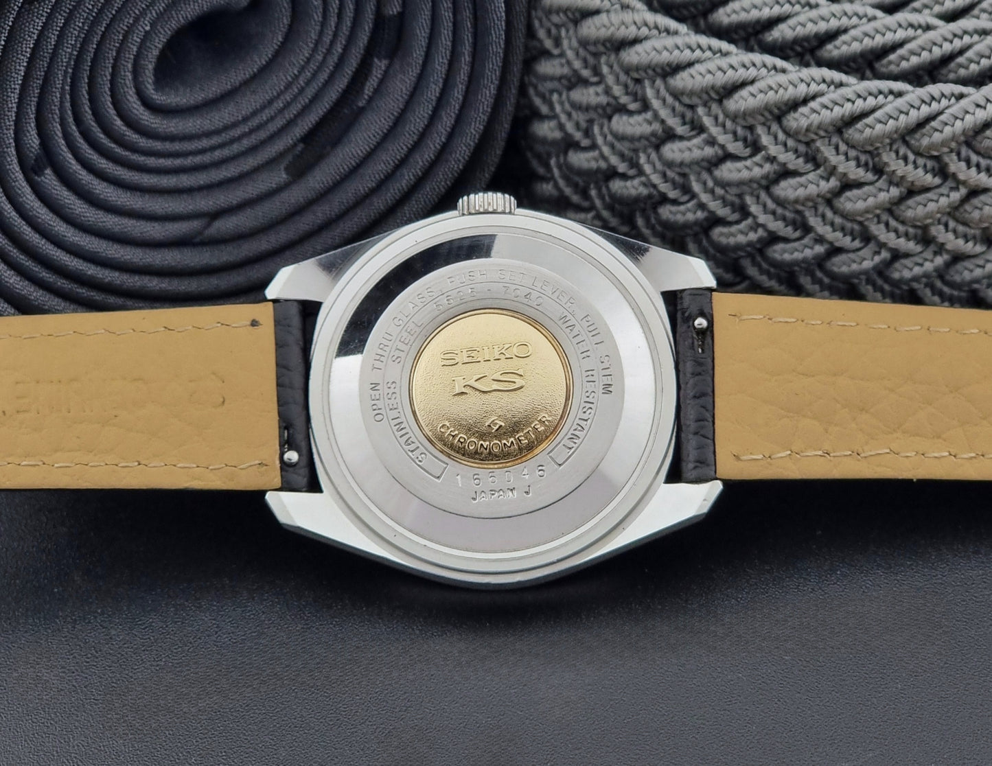 Vintage King Seiko 5625-7040 wrist watch with a black leather strap on a textured dark background case back view