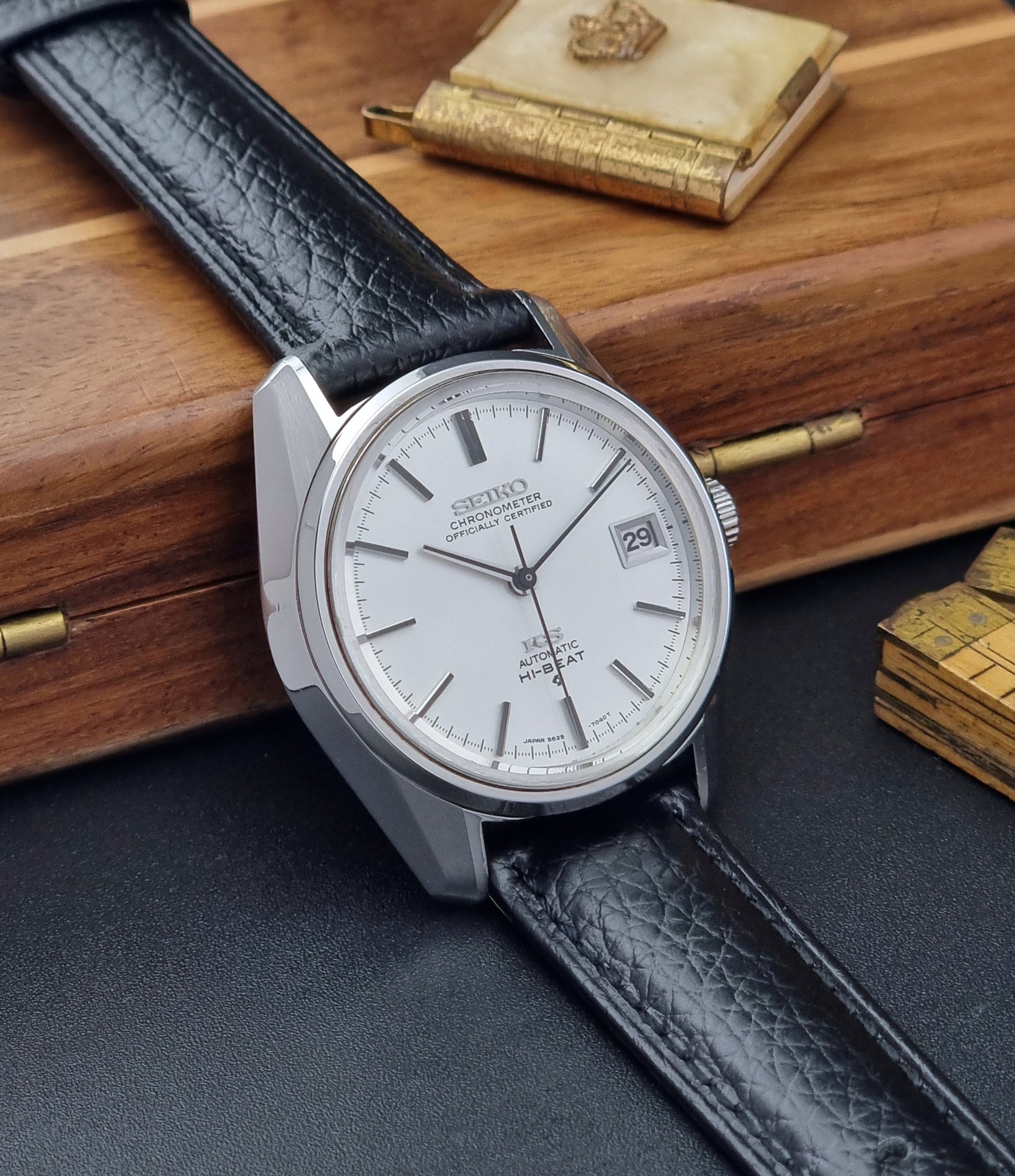 Vintage King Seiko 5625-7041 Wristwatch with black leather strap on a wooden surface side view