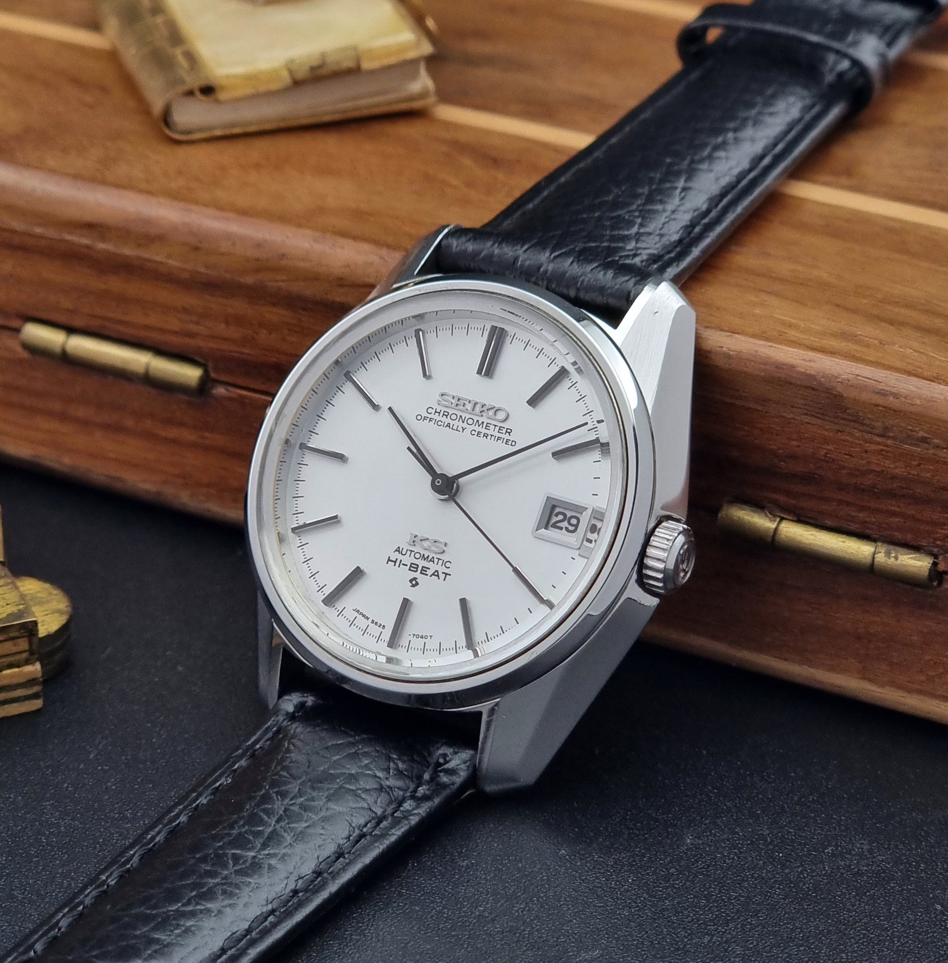 Vintage King Seiko 5625-7041 Wristwatch with black leather strap on a wooden surface crown view