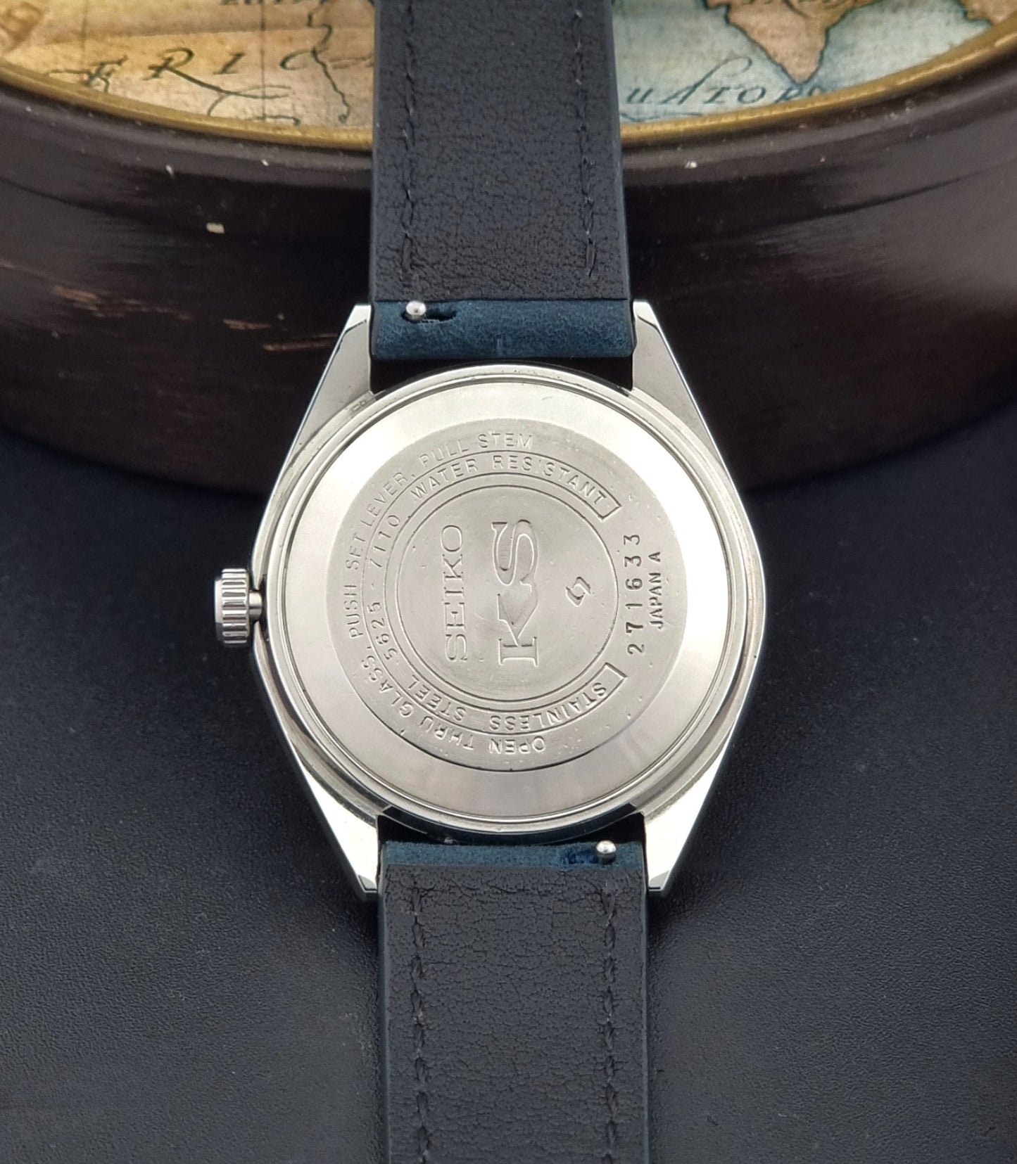 Vintage King Seiko Wristwatch 5625-7110 blue strap and silver case on a dark surface case back view