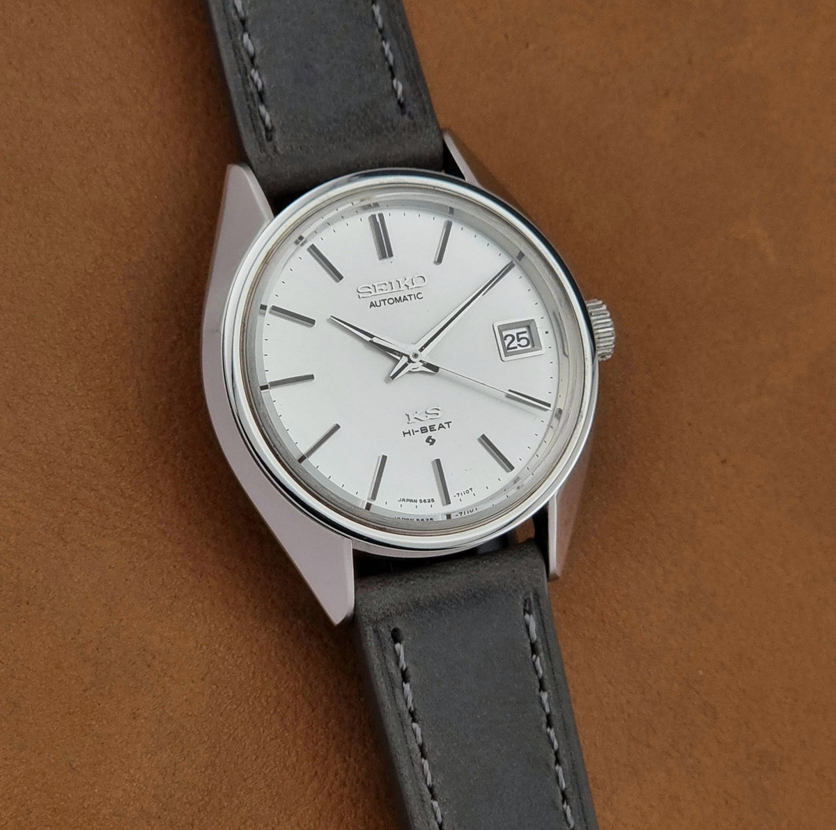 Vintage King Seiko 5625-7110 Wristwatch with a gray strap and white dial on a brown background front view