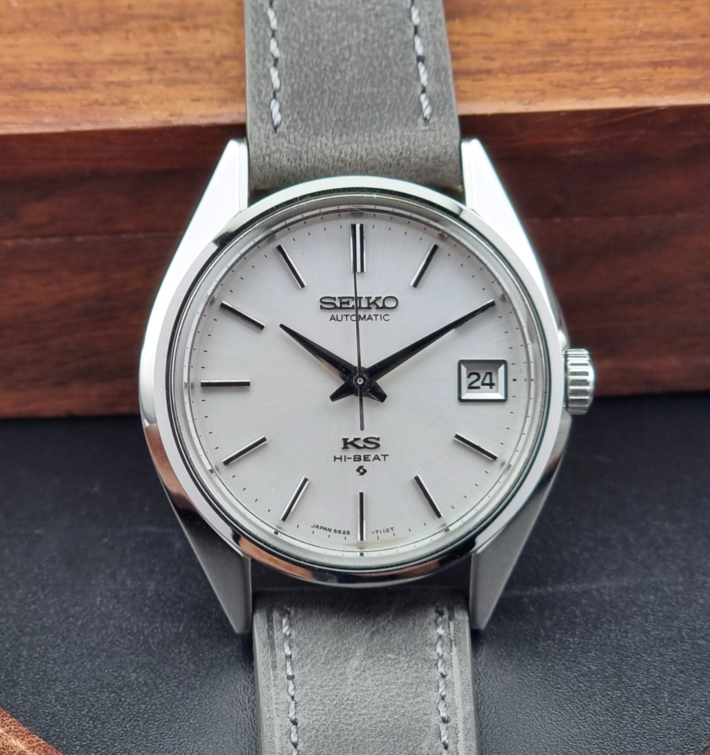 Vintage King Seiko watch with gray strap on a dark surface with wooden background