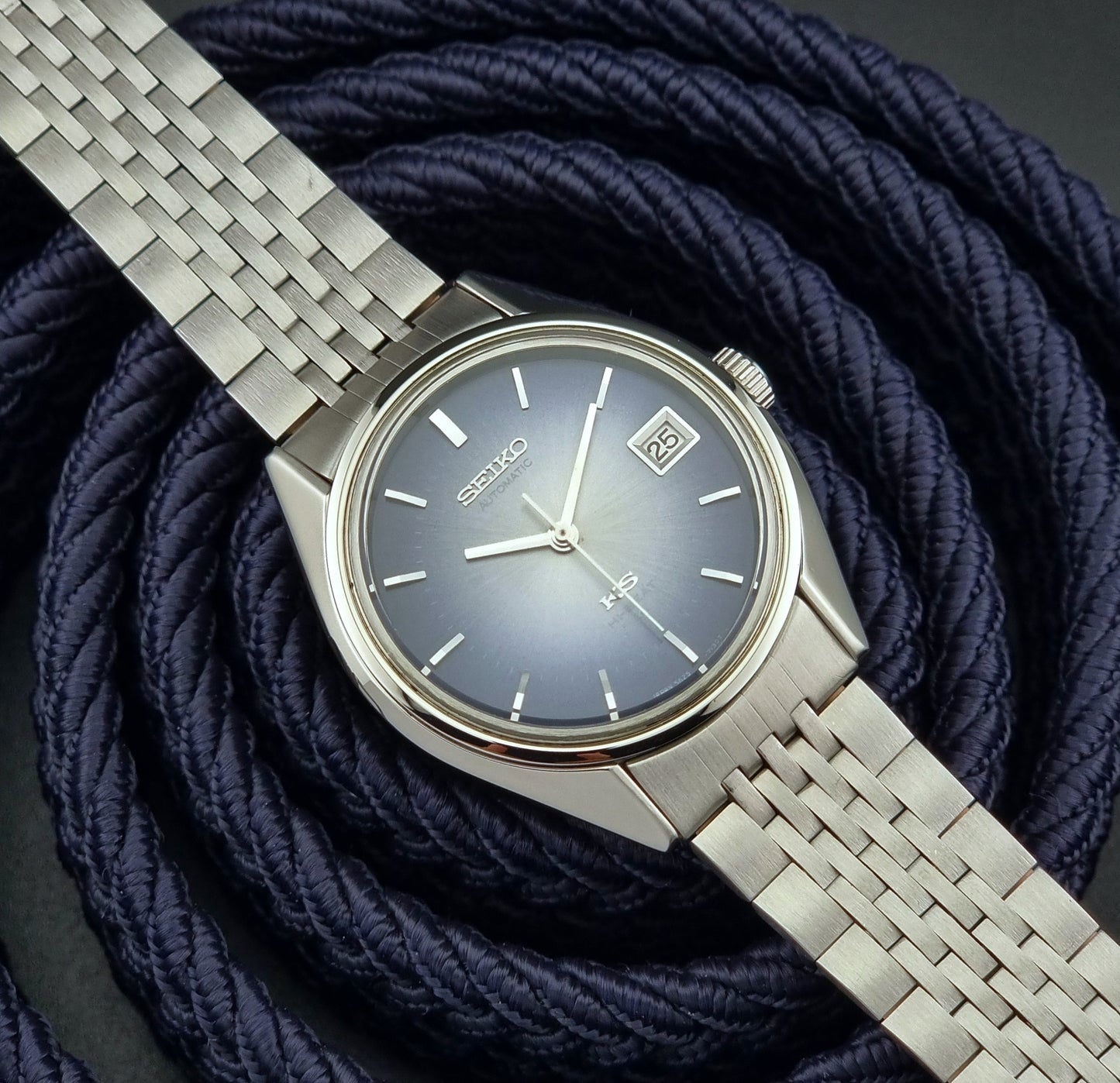 Silver King Seiko watch with a blue dial on a coiled navy blue rope background