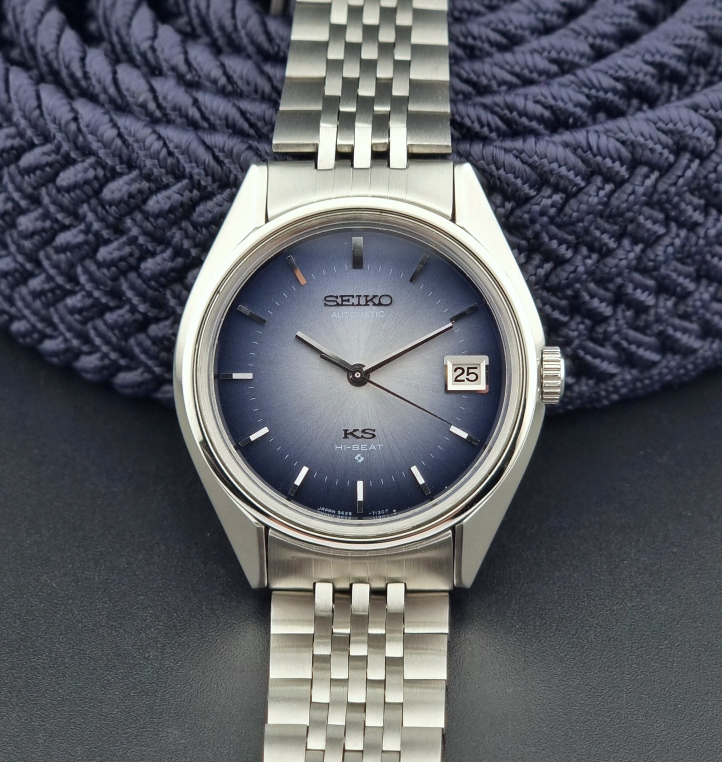 Silver King Seiko watch with blue dial on a textured blue fabric background