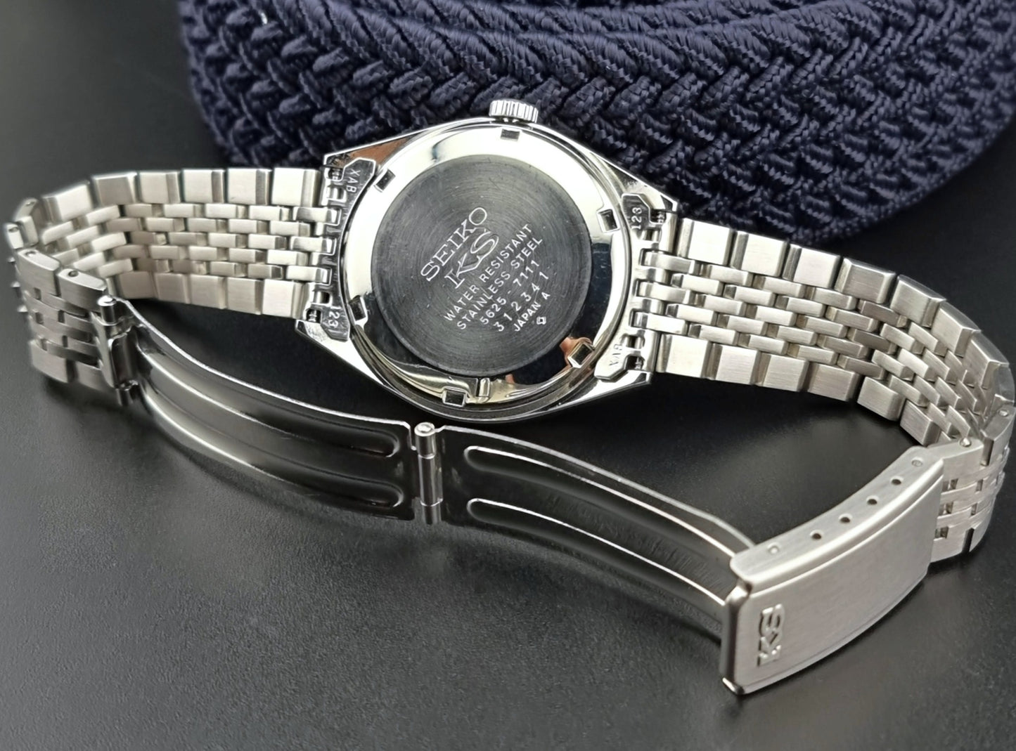 Silver watch with a detailed back cover on a dark surface