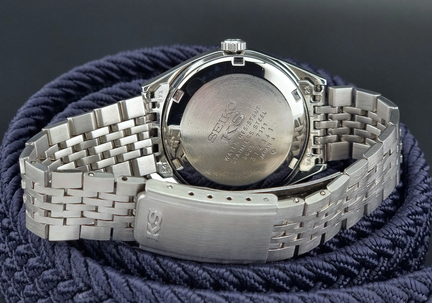 Silver watch with a textured band on a dark background