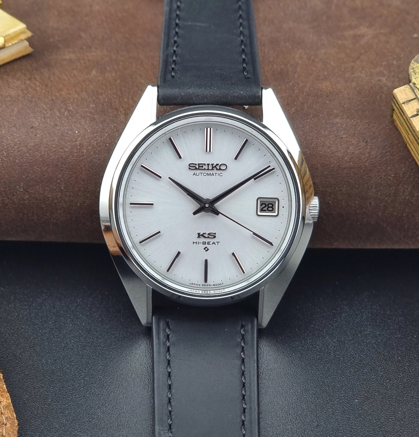 Vintage King Seiko watch with black leather strap on a textured surface