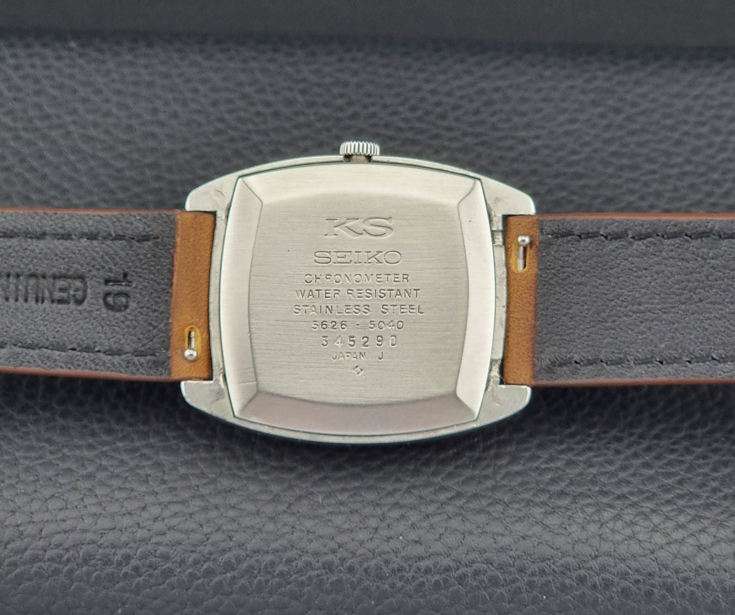Vintage King Seiko 5626-5040 watch case back with brown leather strap on a textured gray background