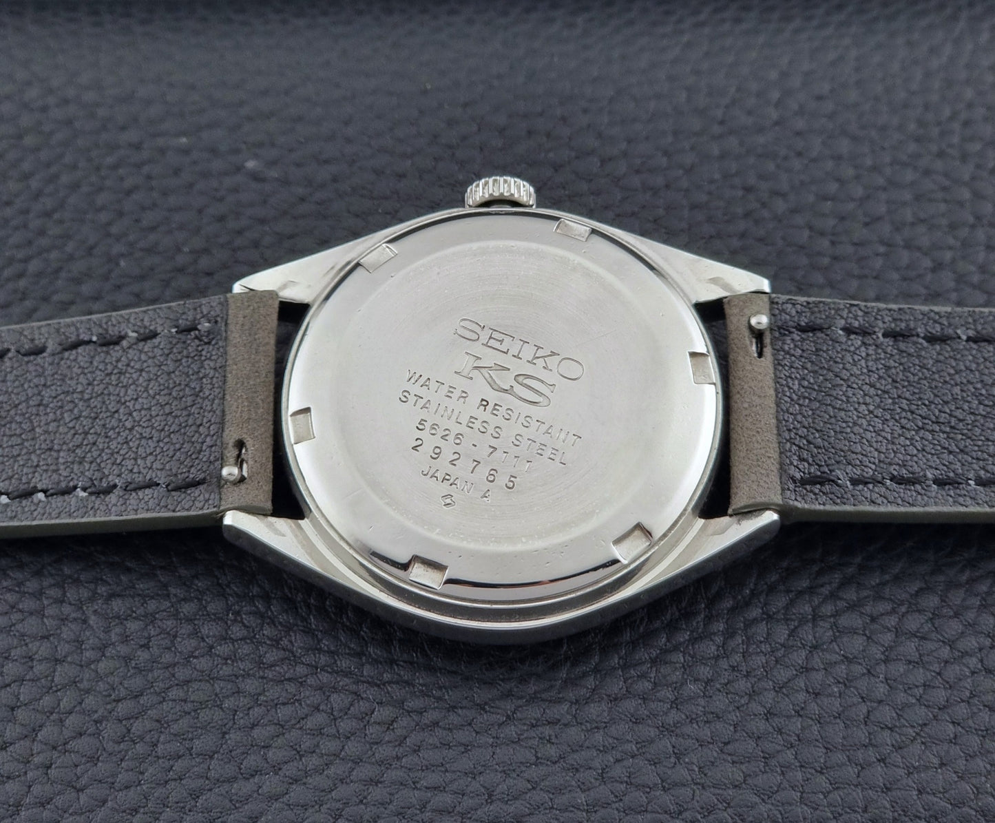 Vintage King Seiko Wristwatch 5626-7111 with a graduated blue dial and gray leather strap on a textured dark background case back