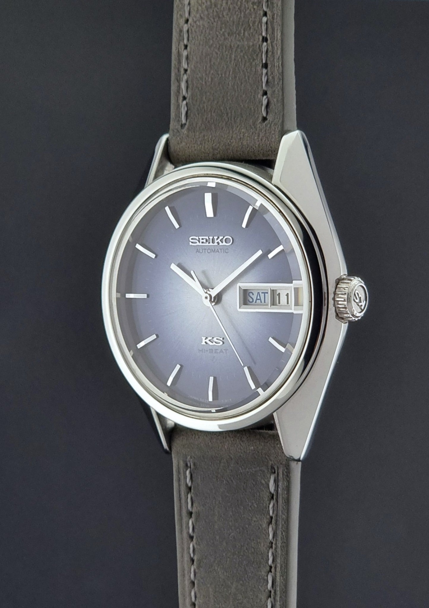 Vintage King Seiko Wristwatch 5626-7111 with a blue dial and gray leather strap on a textured dark background crown side profile