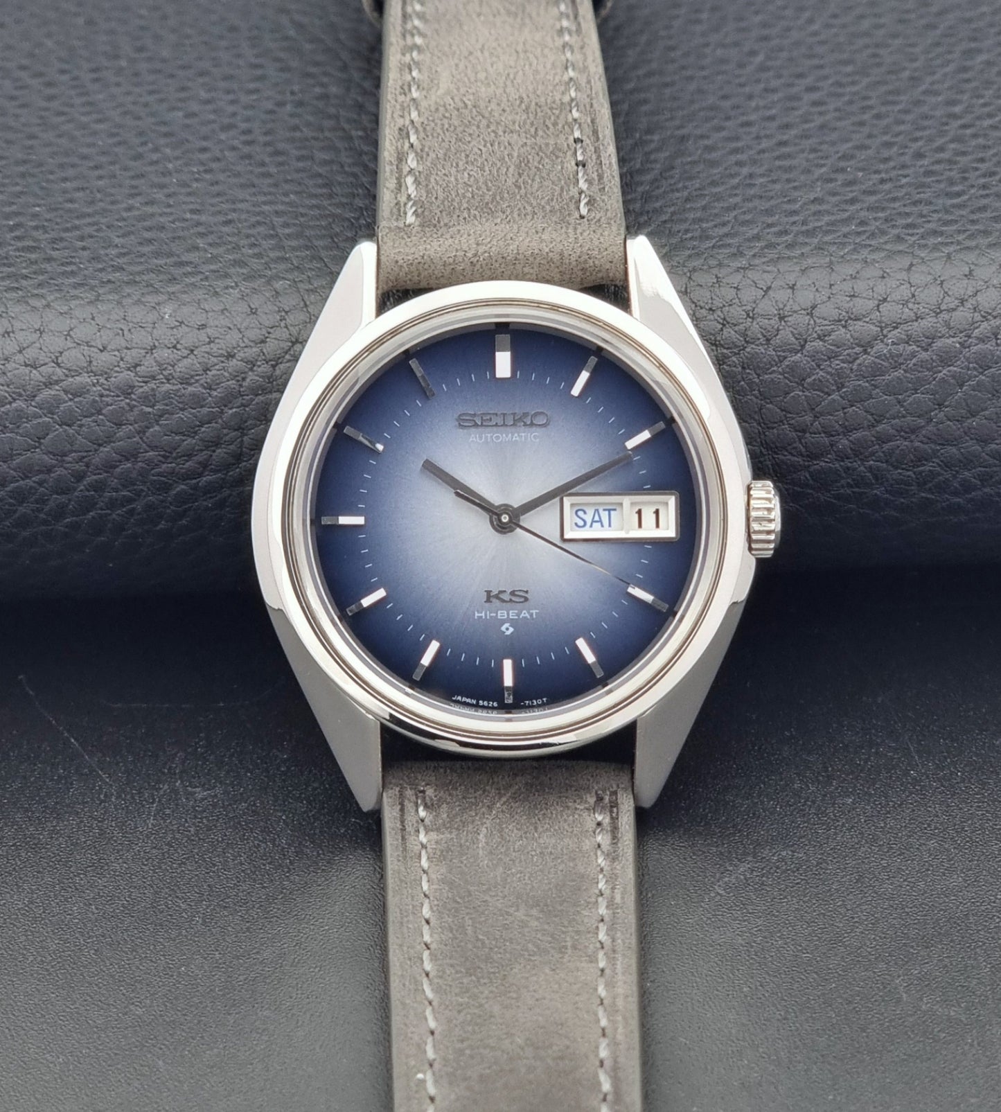 Vintage King Seiko Wristwatch 5626-7111 with a blue dial and gray leather strap on a textured dark background front