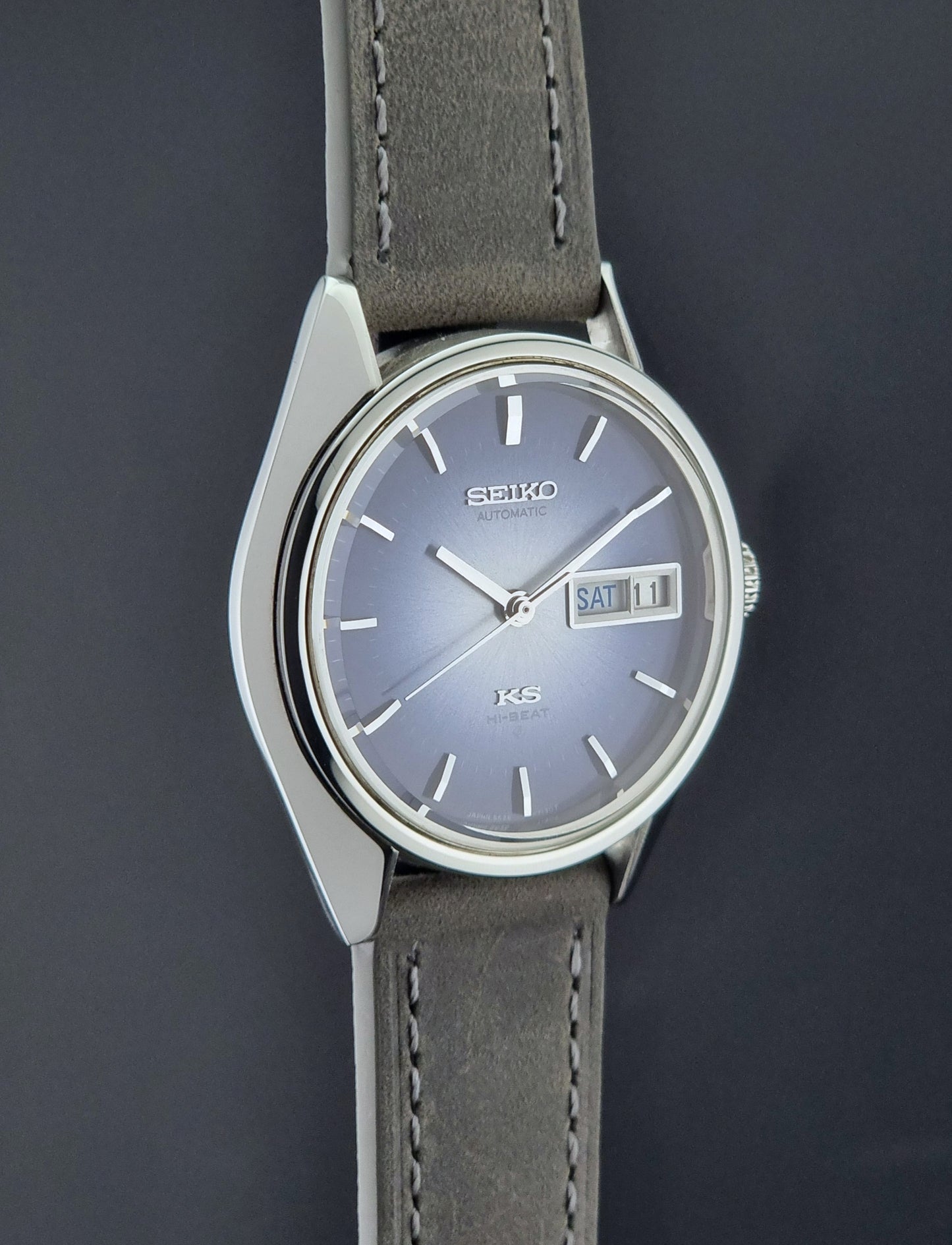 Vintage King Seiko Wristwatch 5626-7111 with a blue dial and gray leather strap on a textured dark background side profile