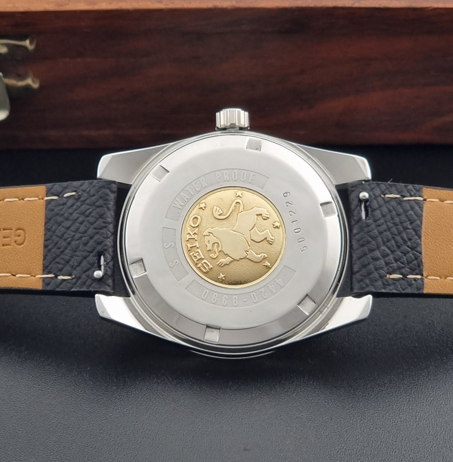 Vintage King Seiko Wristwatch 4420-9990 Chronometer with a black strap on a textured background case back view