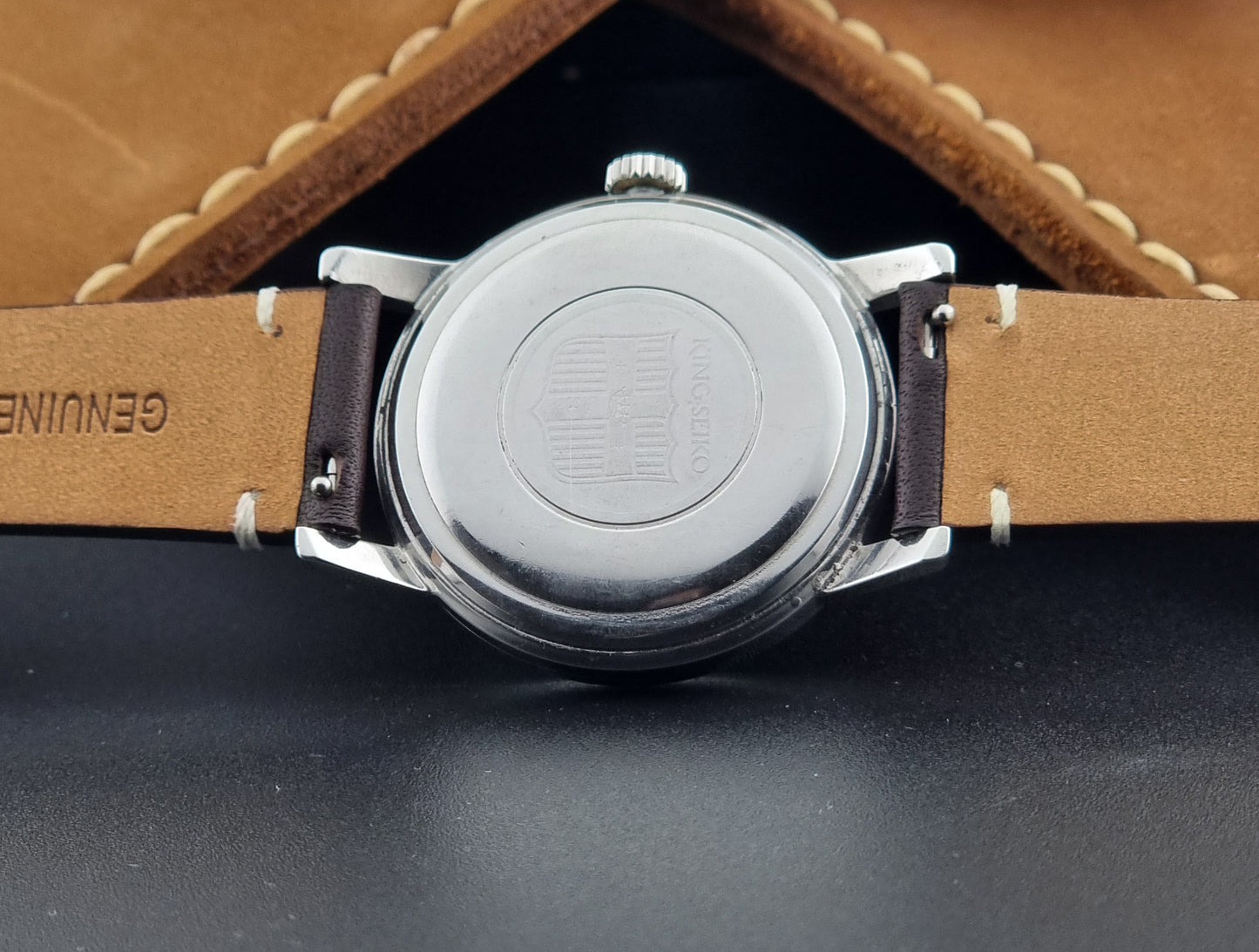 Vintage King Seiko J14102E Wristwatch with brown leather strap on a dark gray background case back