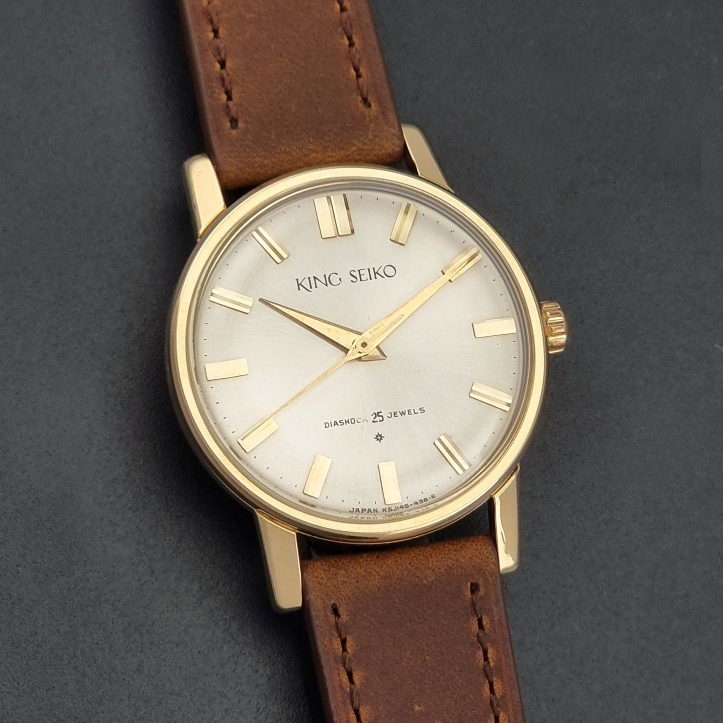 Vintage King Seiko J14102E Watch with brown leather strap on a dark gray background front view