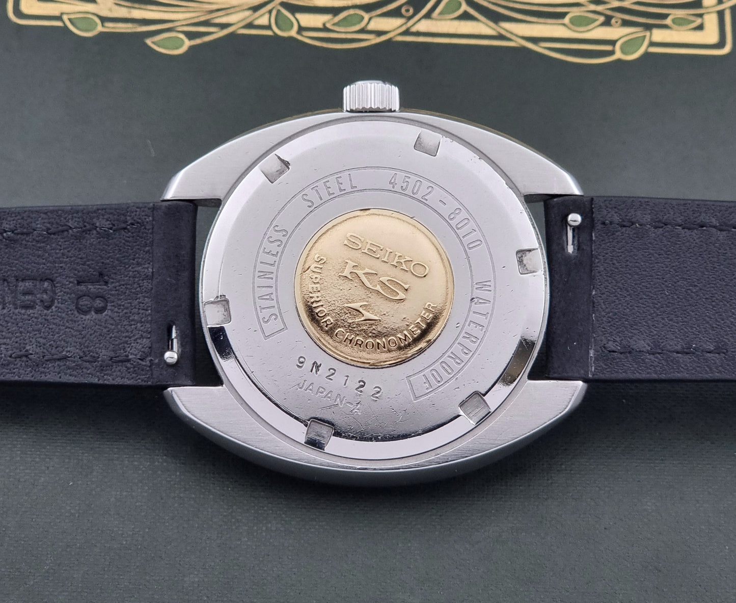 Vintage King Seiko Watch 4502-8010 with black leather strap on a dark surface case back view