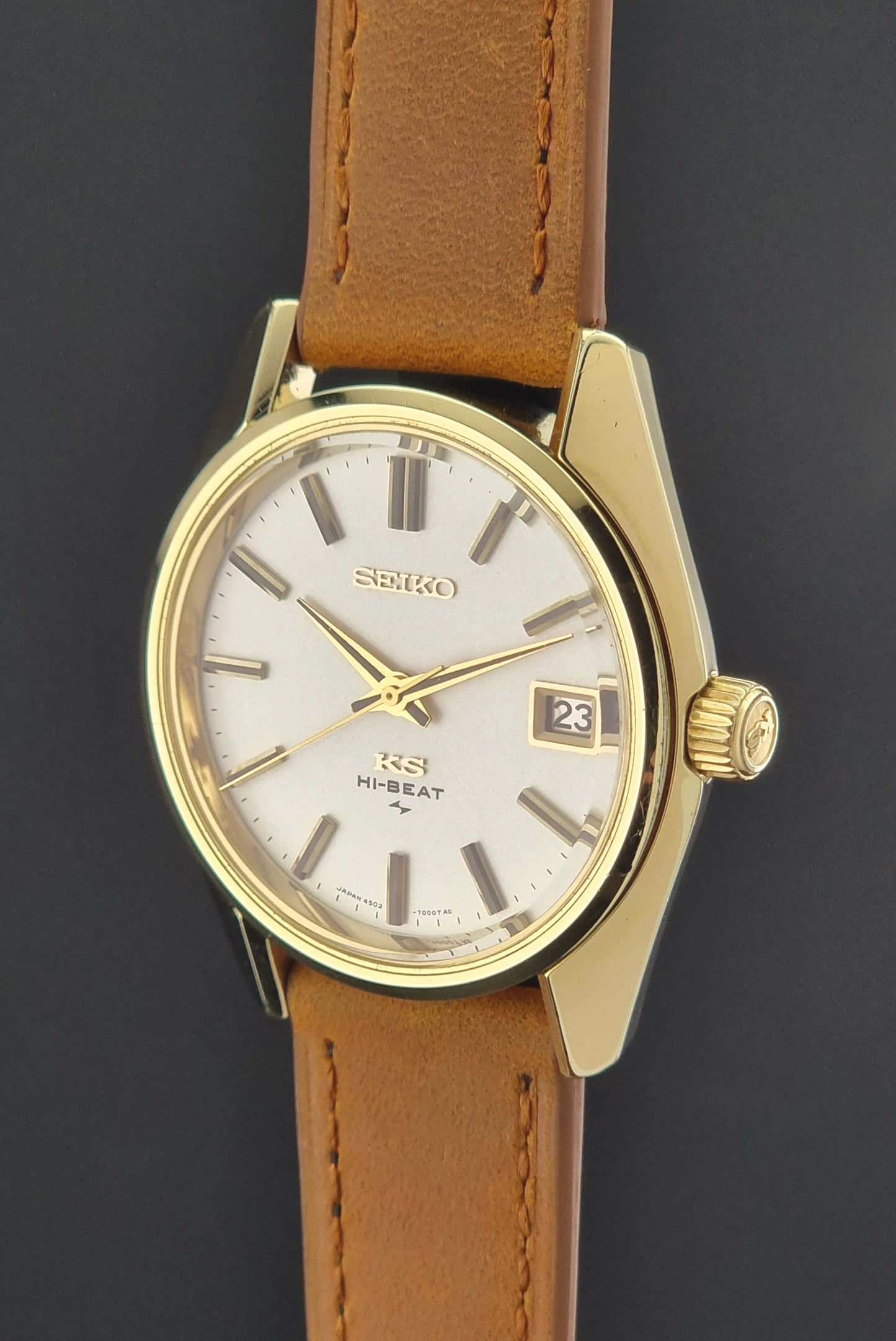 Gold Vintage King Seiko watch with a brown leather strap on a dark background