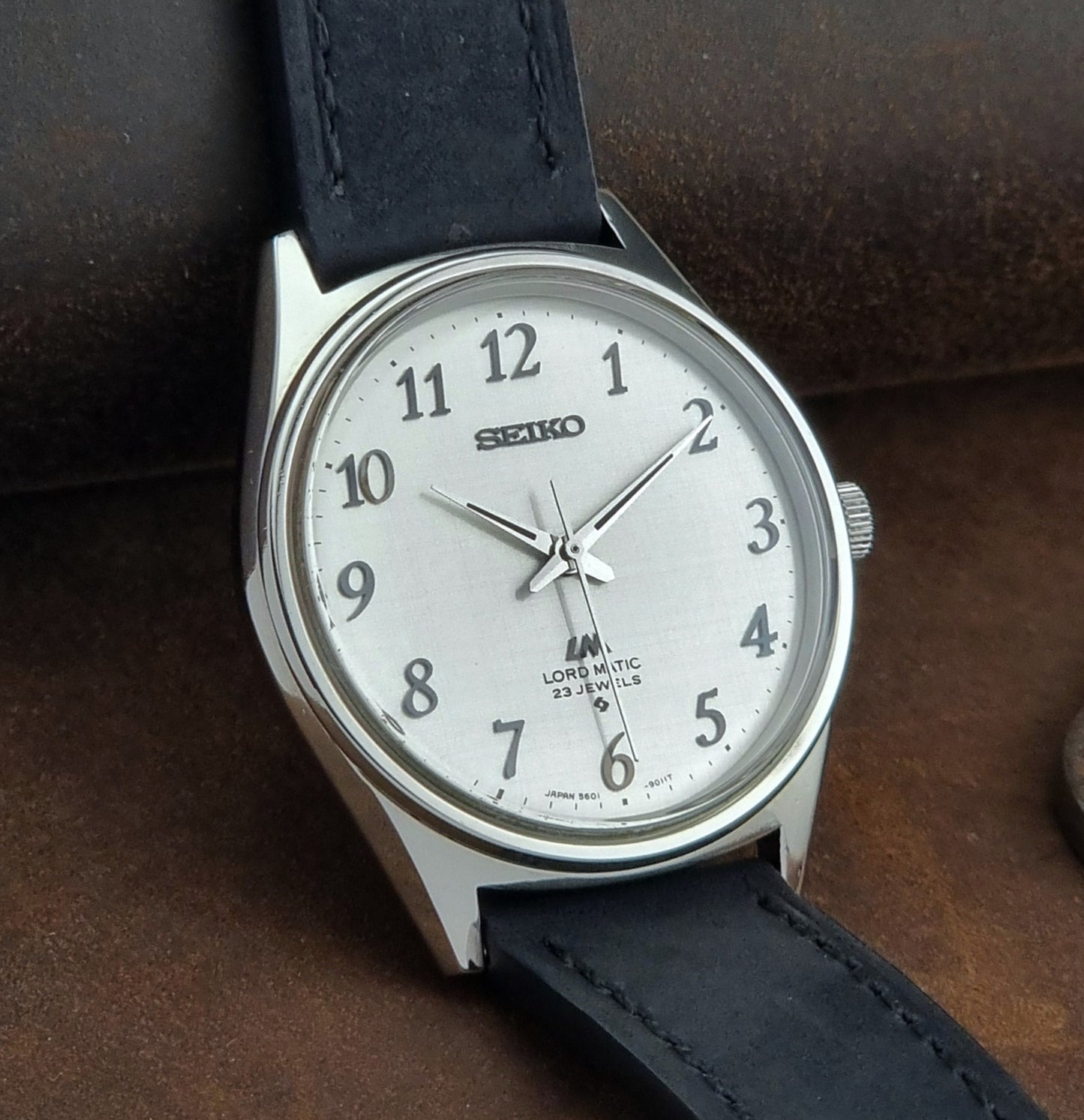 Seiko watch with black leather strap on a brown background