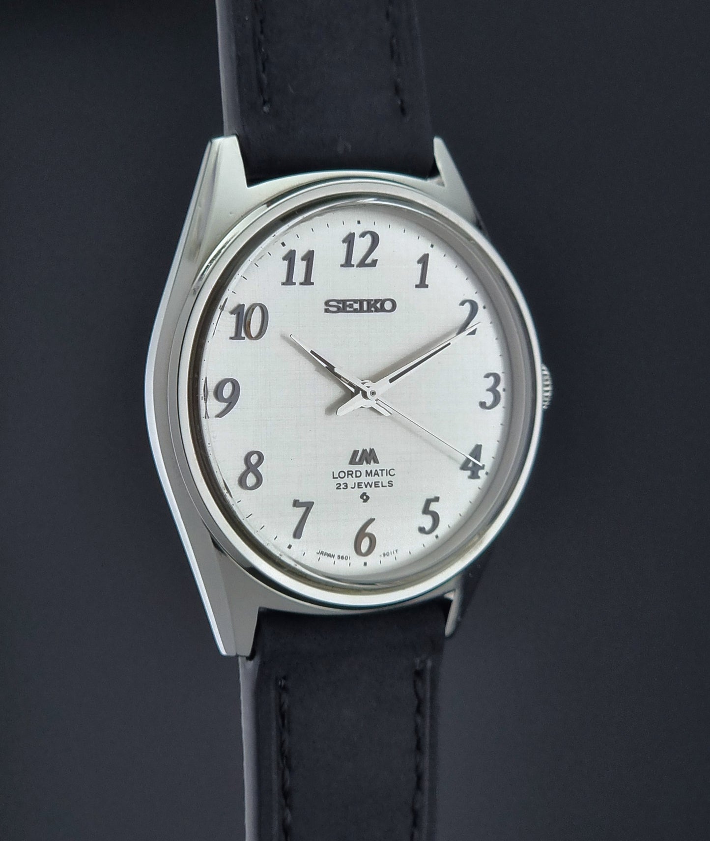 Seiko watch with black leather strap on a dark background