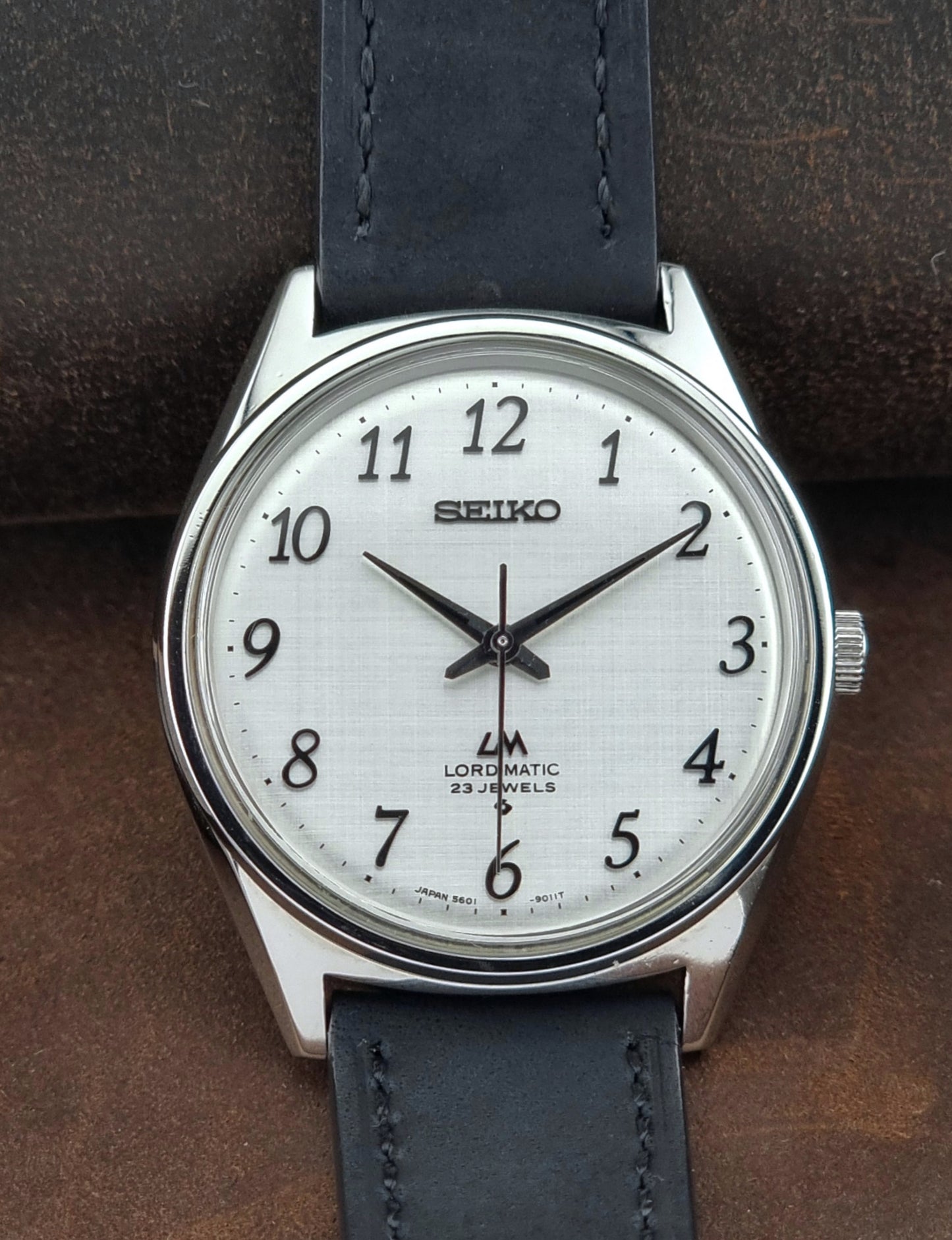 Seiko watch with a blue leather strap on a brown background