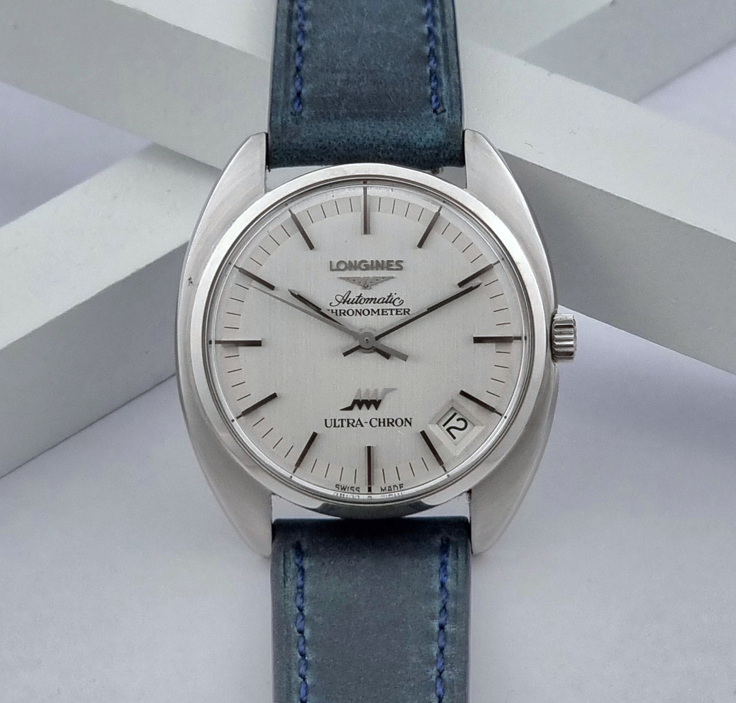 Vintage Longines Wristwatch ULTRA-CHRON 8353-5 Chronometer with a blue leather strap on a light gray background front view