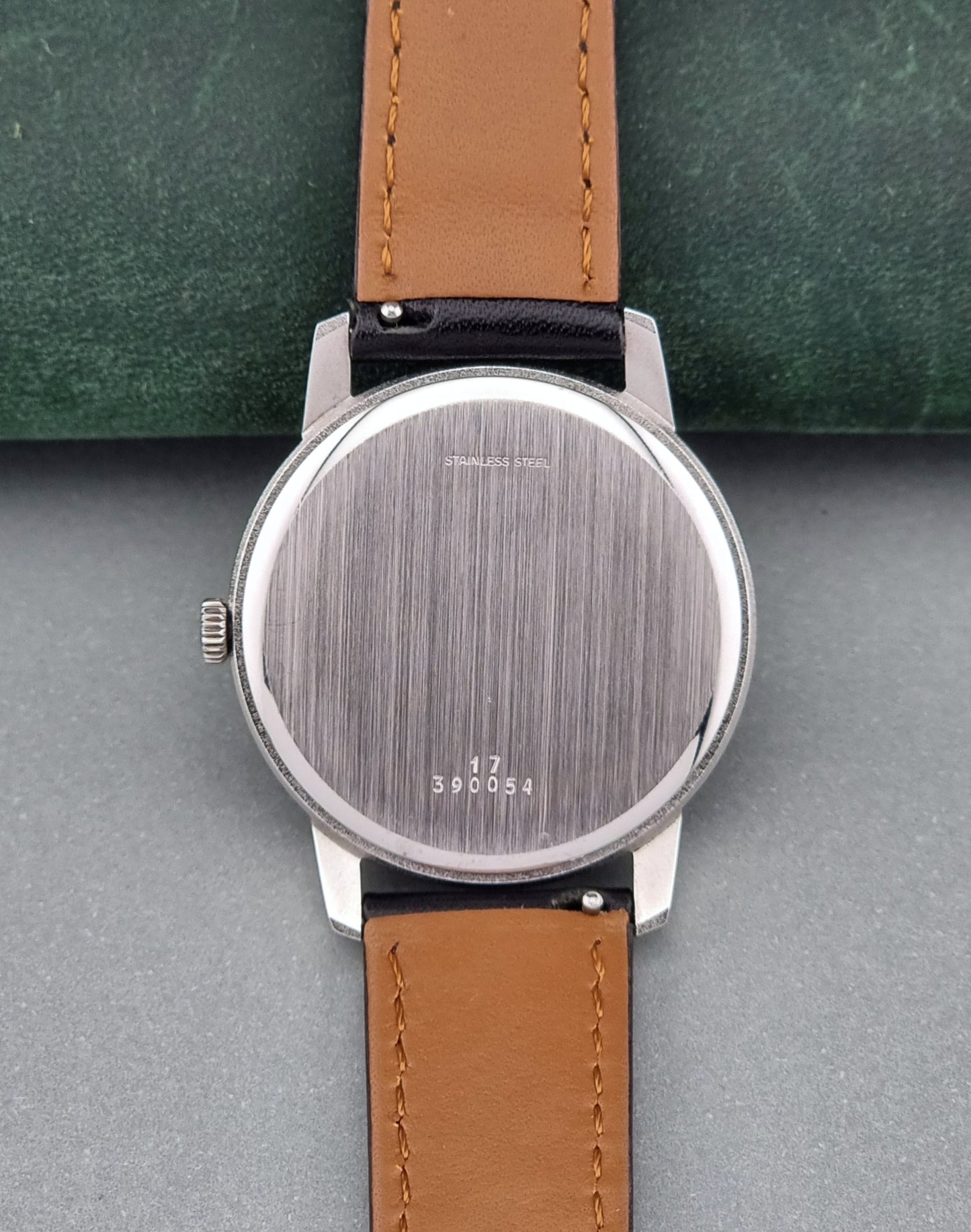 Vintage Longines watch case back on a green surface