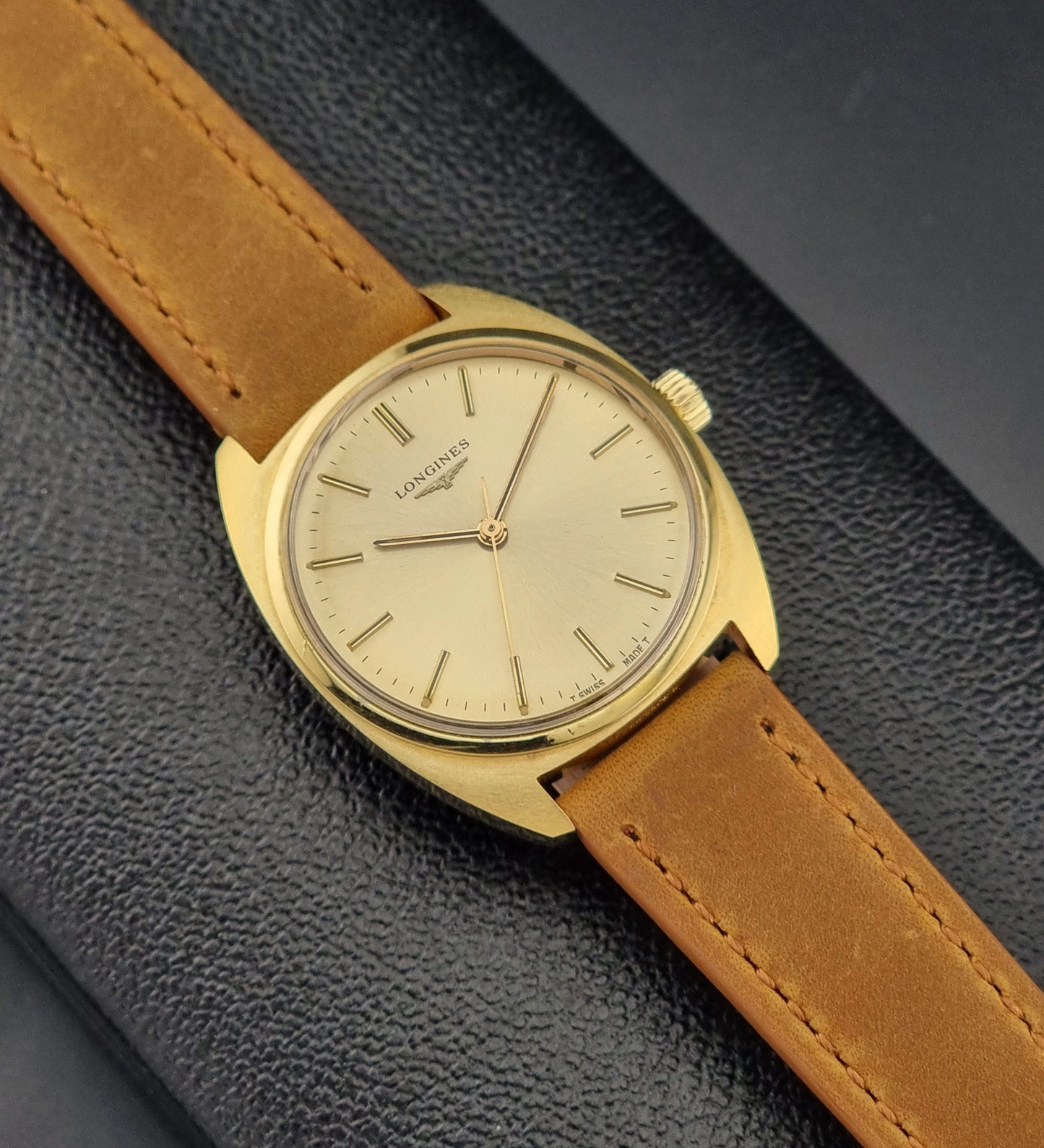 Vintage Gold Longines watch with a brown leather strap on a dark textured background