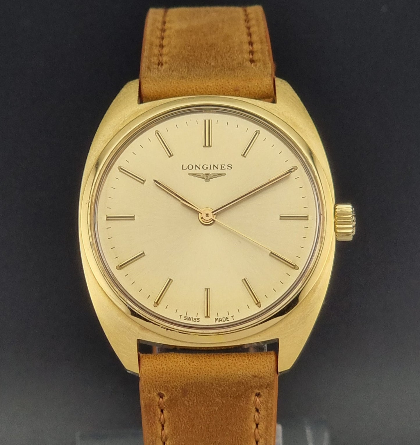 Front view of a Vintage Gold Longines wristwatch with brown leather strap on a black background